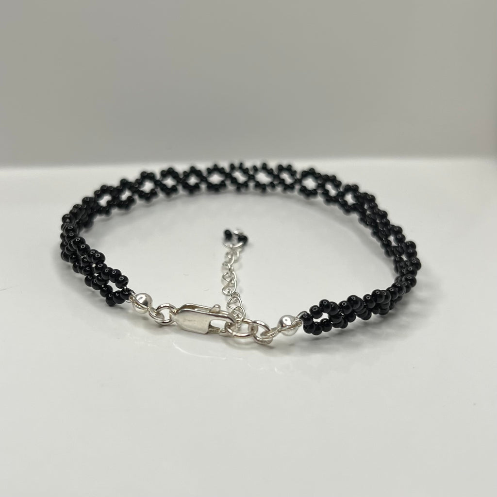 Black beaded bracelet with silver clasp on a white surface