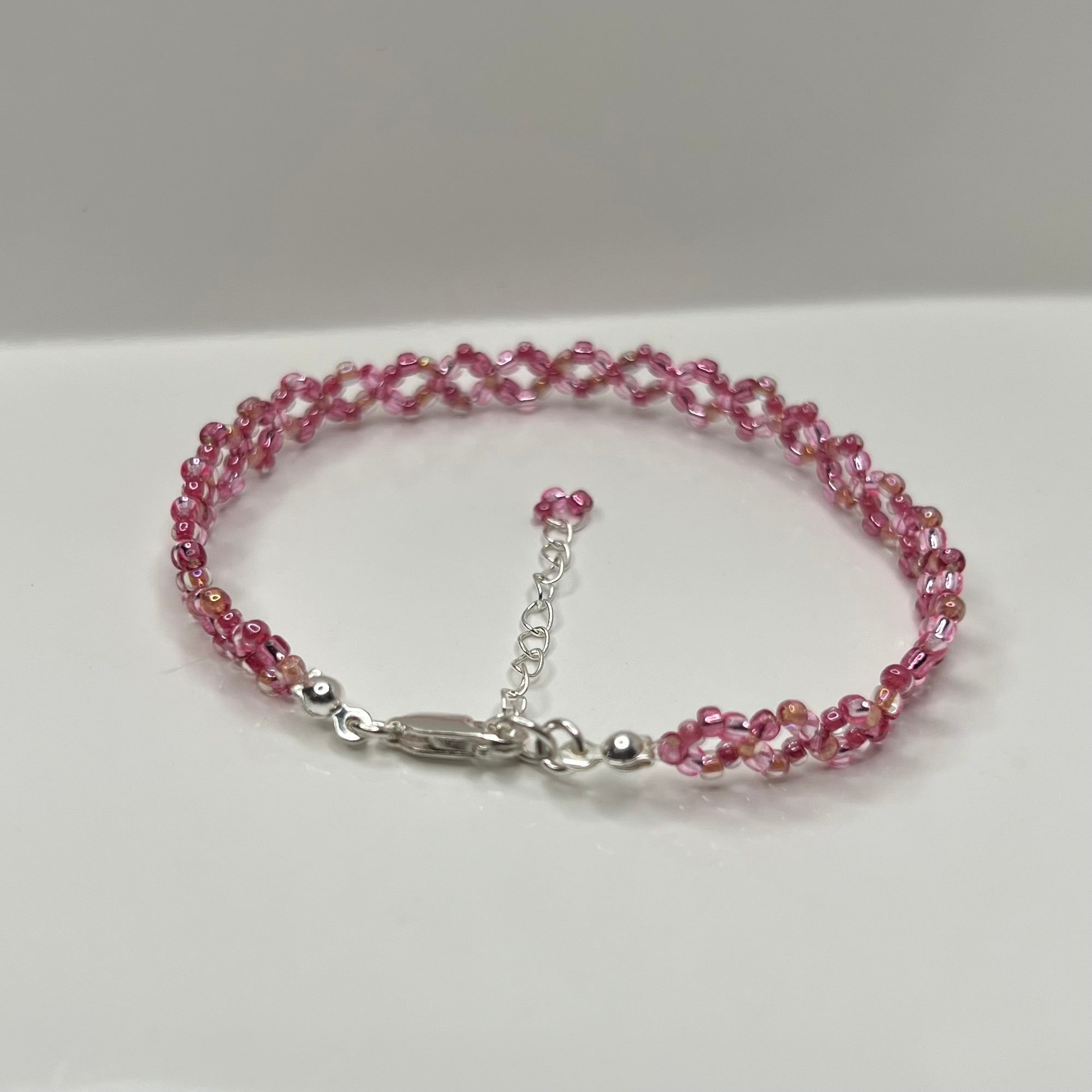Pink beaded bracelet with a silver clasp on a white background