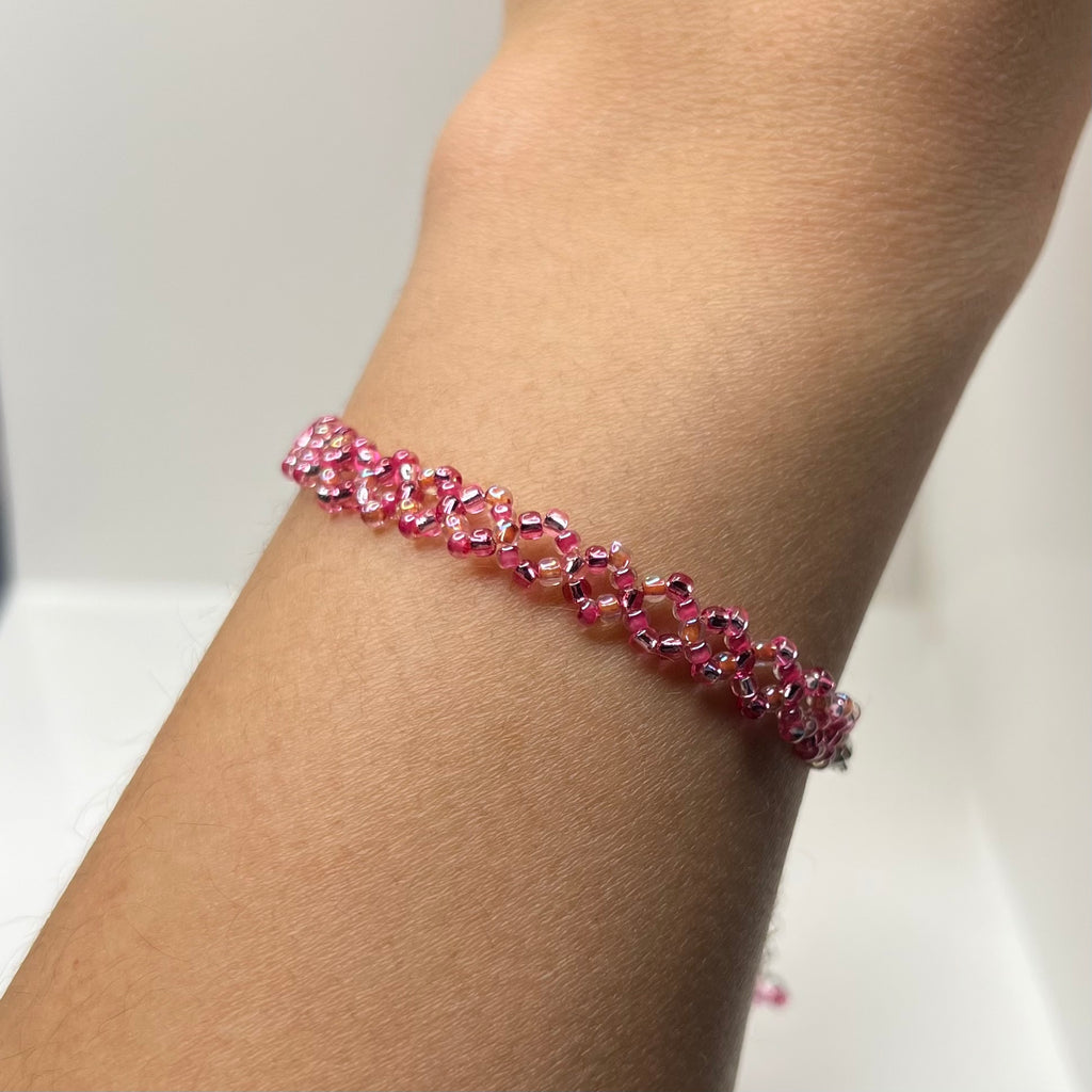 Pink beaded bracelet on a wrist with a neutral background