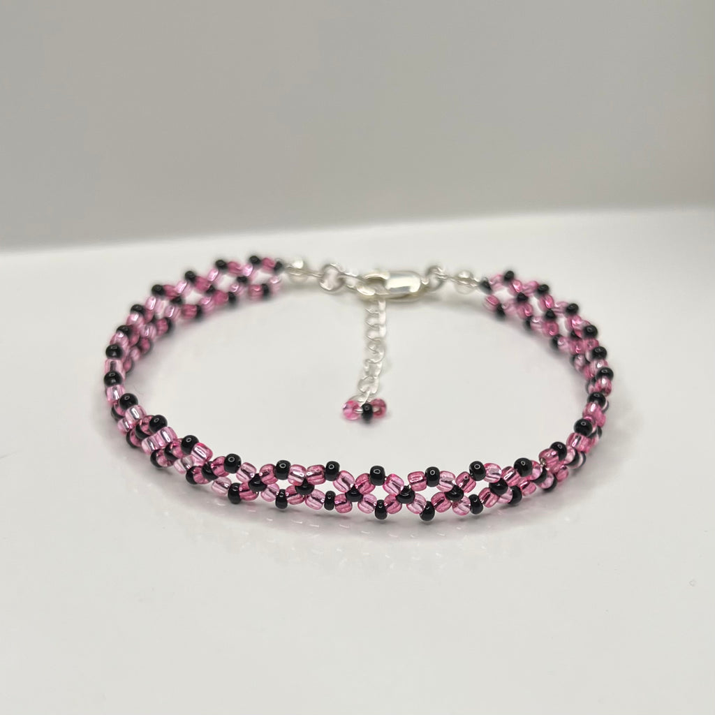 Beaded bracelet with pink and black beads on a white background