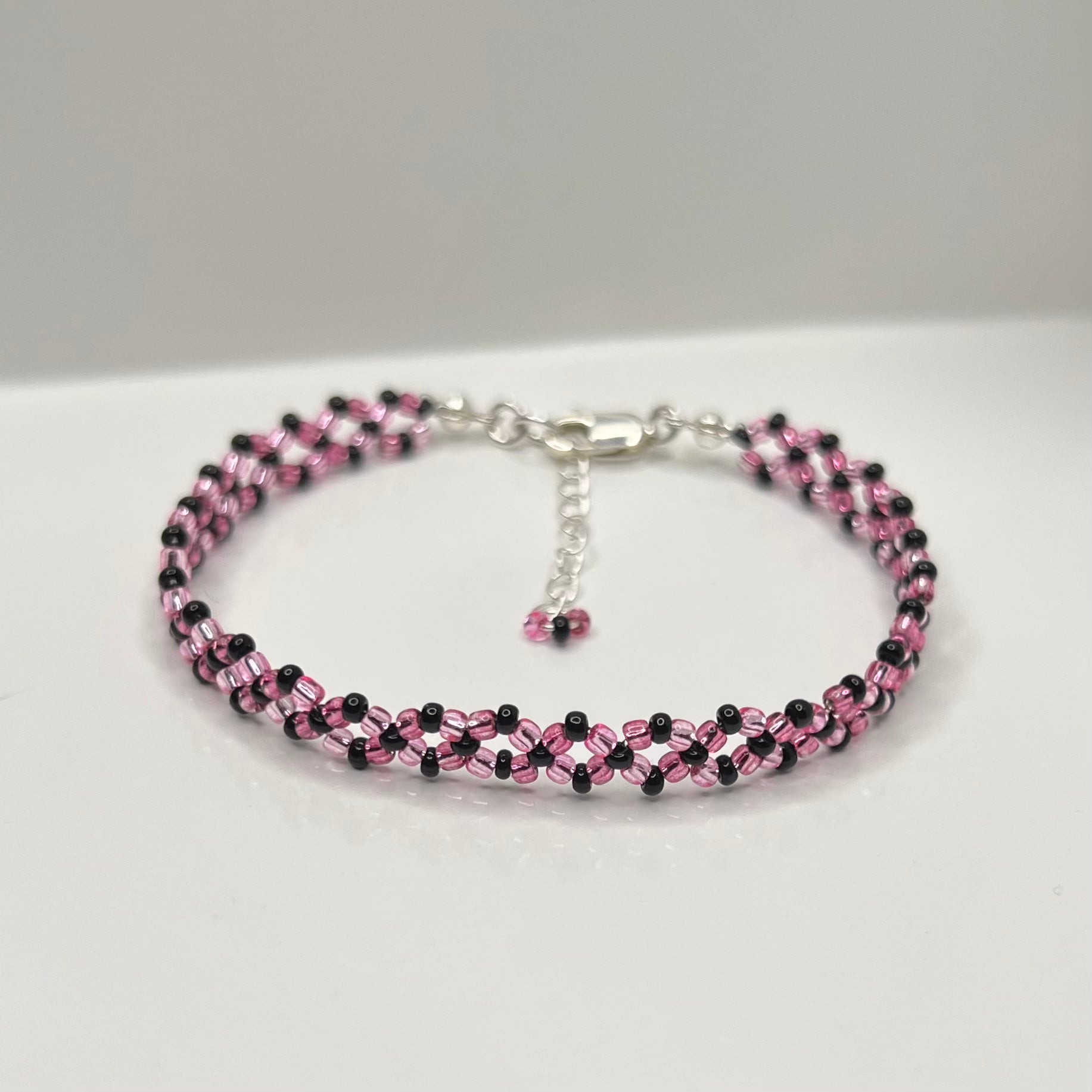 Beaded bracelet with pink and black beads on a white background