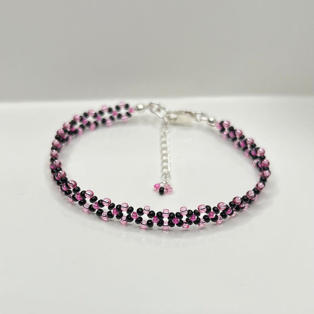Beaded necklace with pink and black beads on a white background