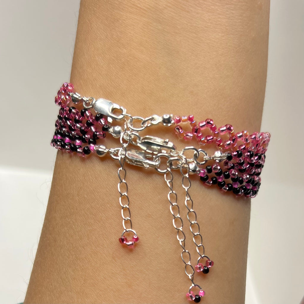 Bracelet with pink and black beads on a wrist against a neutral background
