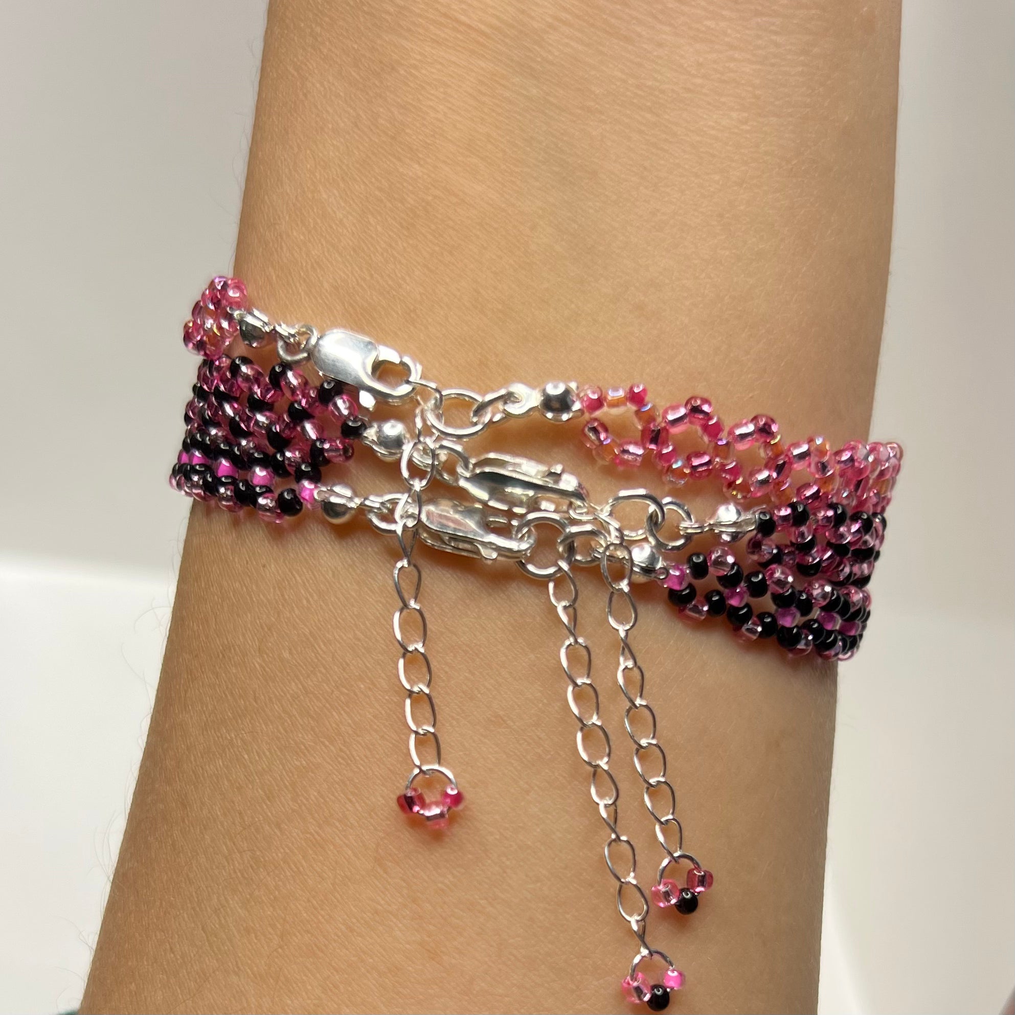 Bracelet with pink and black beads on a wrist against a neutral background