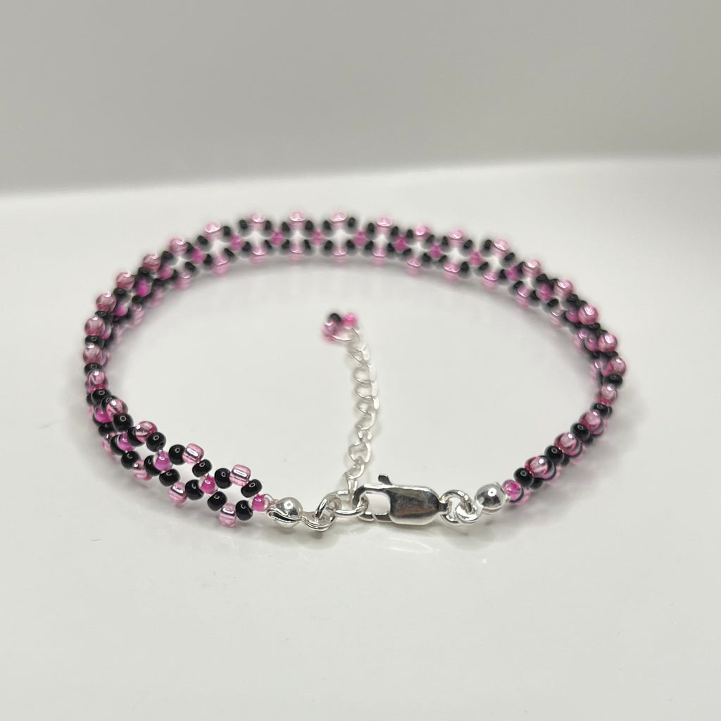Beaded bracelet with pink and black beads on a white background