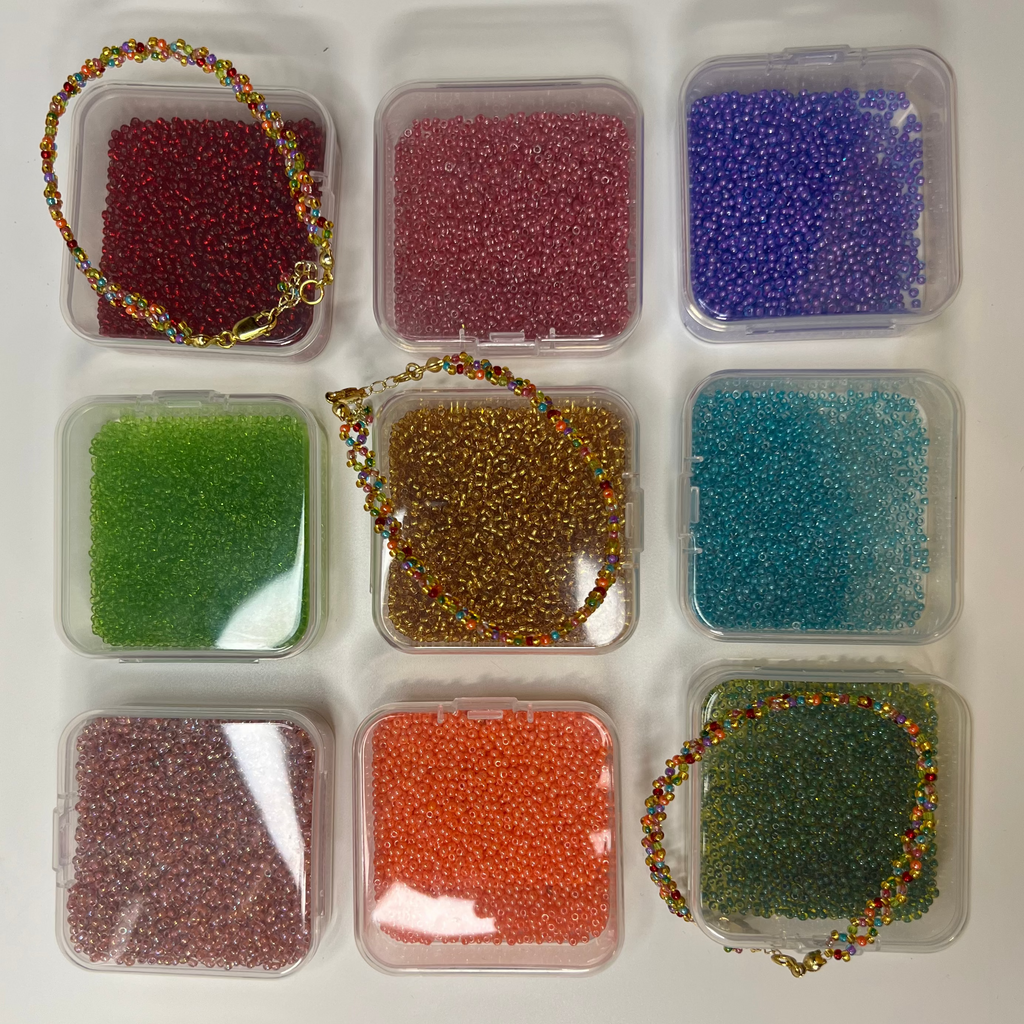 Assorted colored beads on clear containers with beaded bracelets on a white background