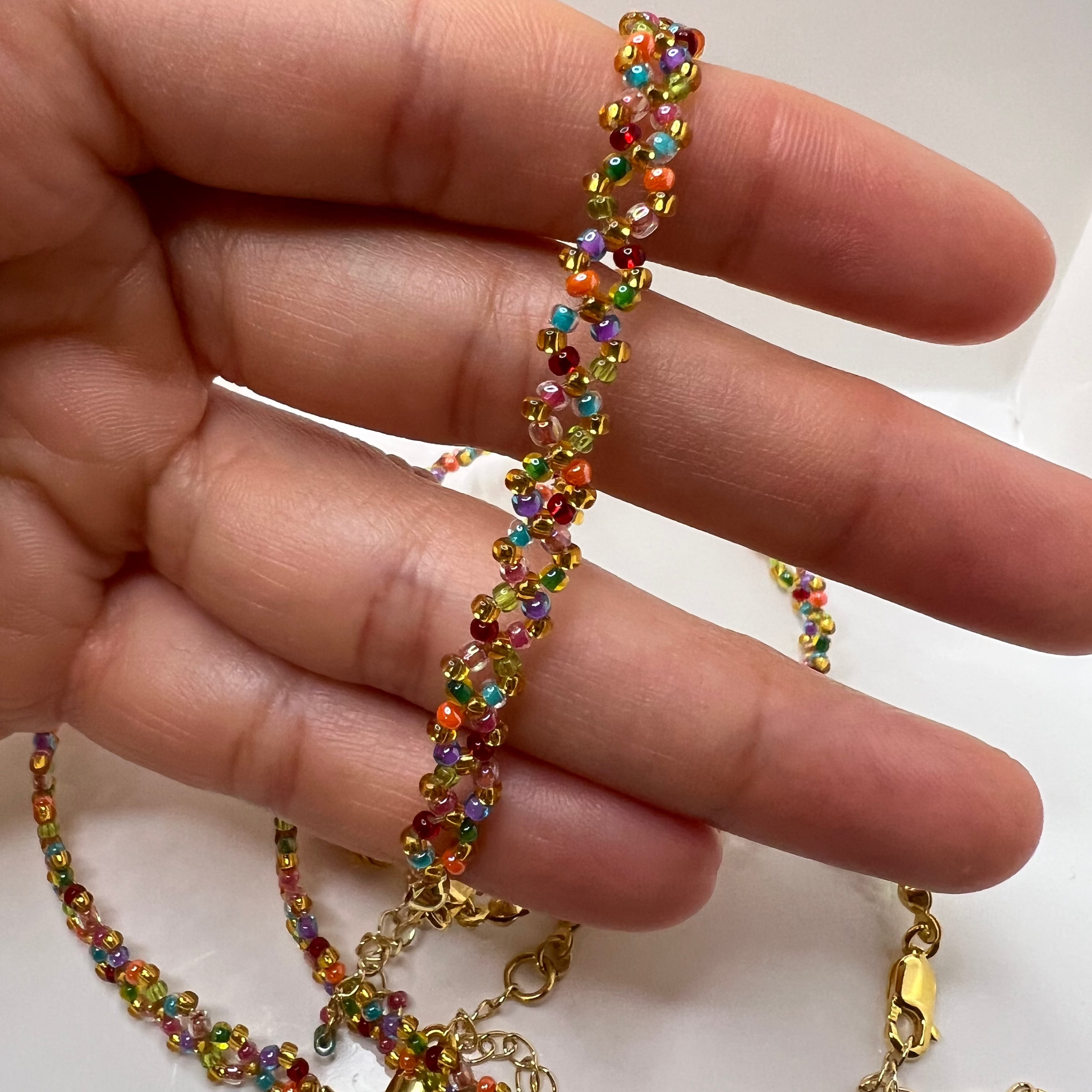 Multicolored beaded bracelet on a hand with a plain background