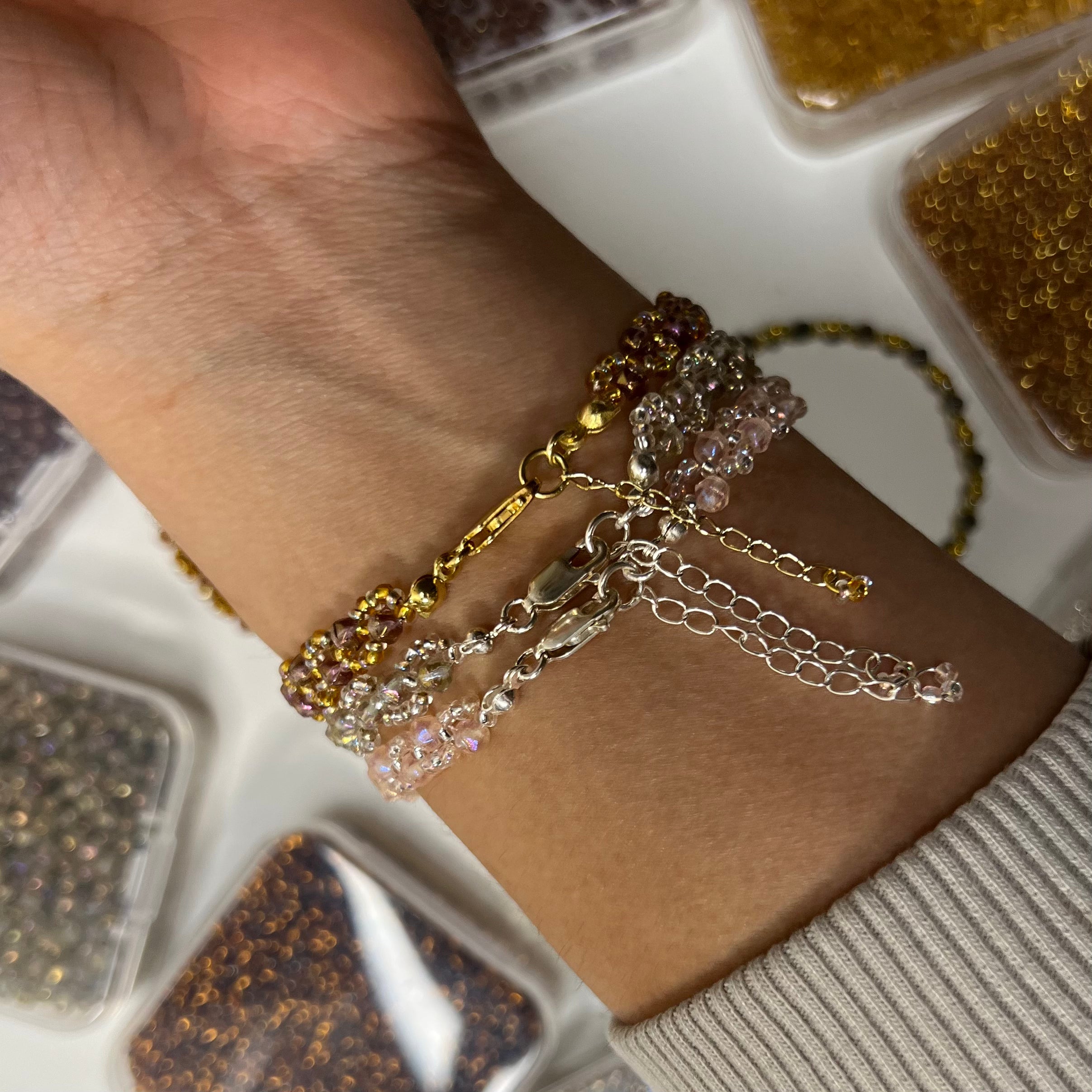 Close-up of a wrist wearing multiple gold and silver bracelets with a blurred background.