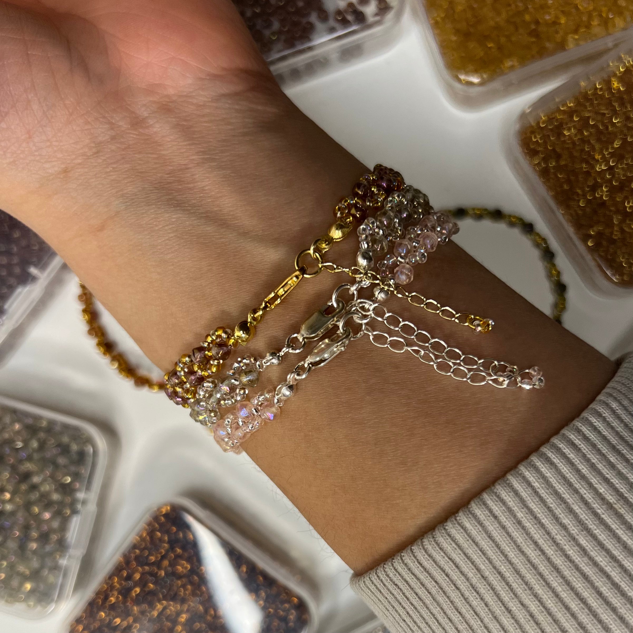 Close-up of a wrist wearing multiple gold and silver bracelets with a blurred background.