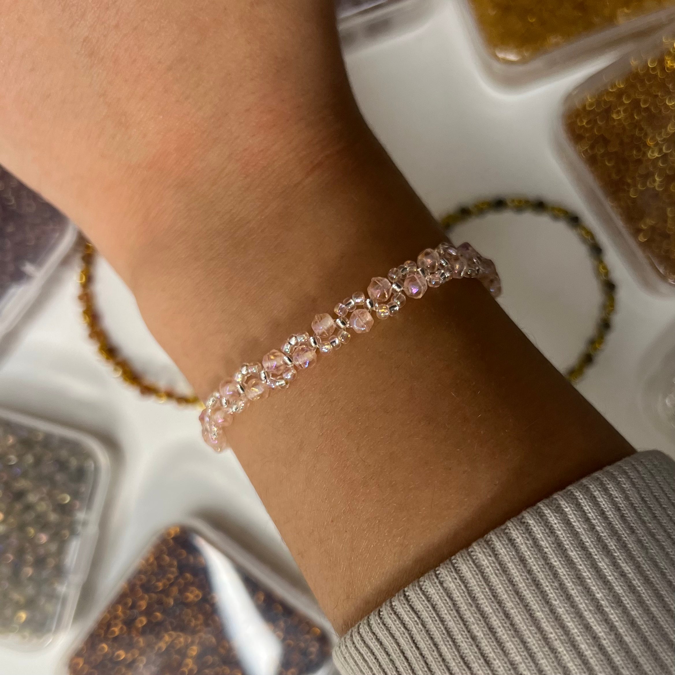 Close-up of a wrist wearing a pink beaded bracelet with a neutral background.