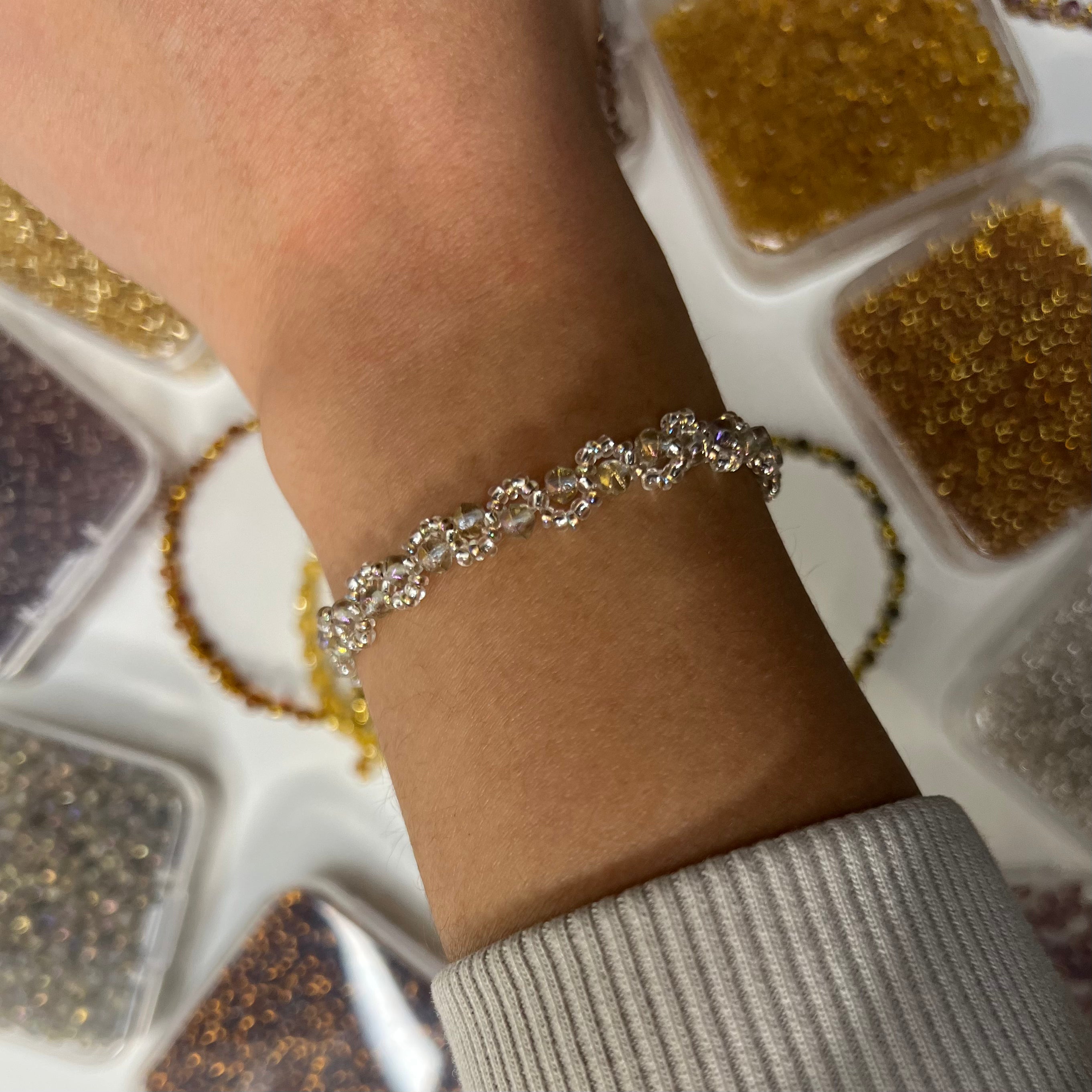 Silver bracelet on a wrist with a background of jewelry trays.