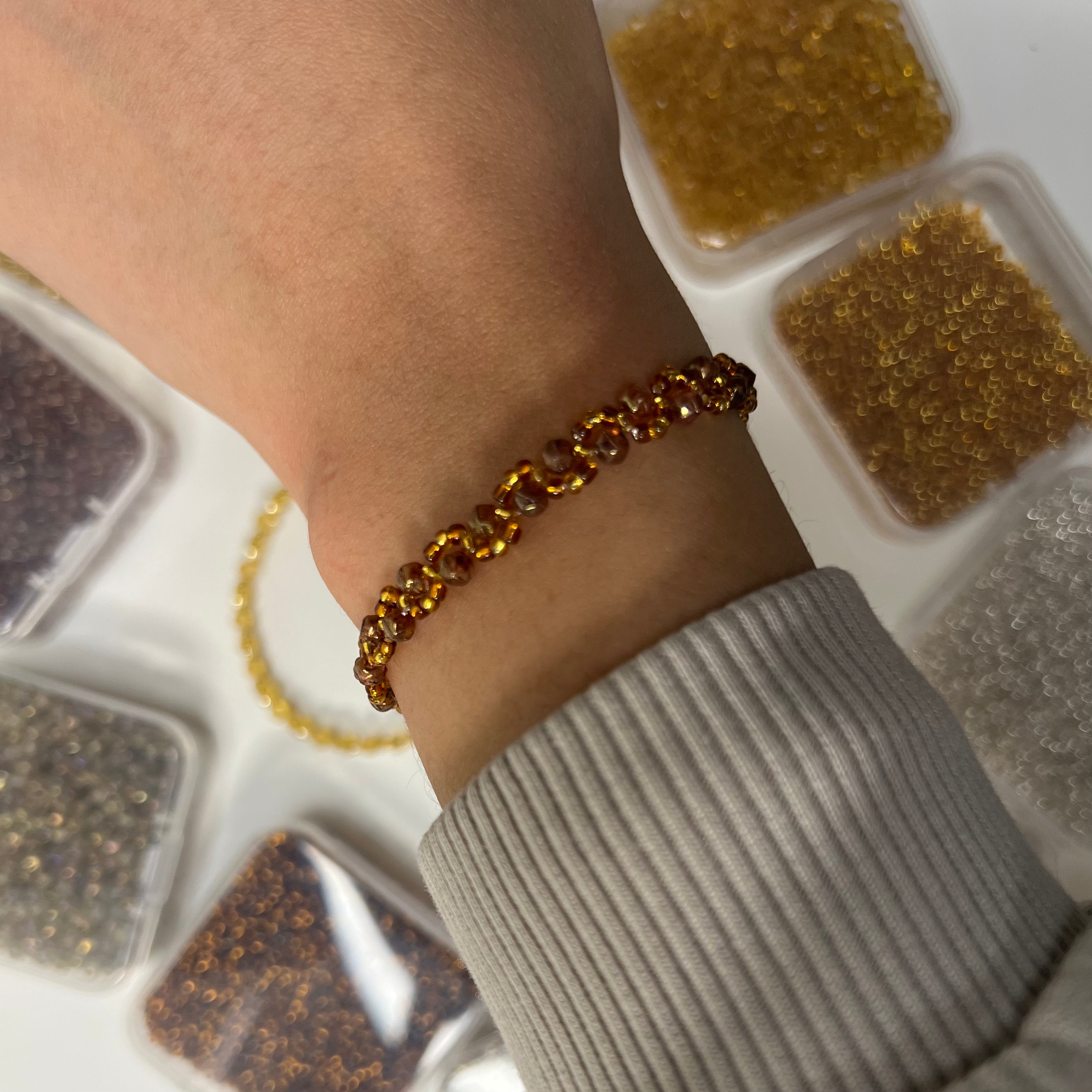 Close-up of a wrist wearing a gold bracelet with a neutral background