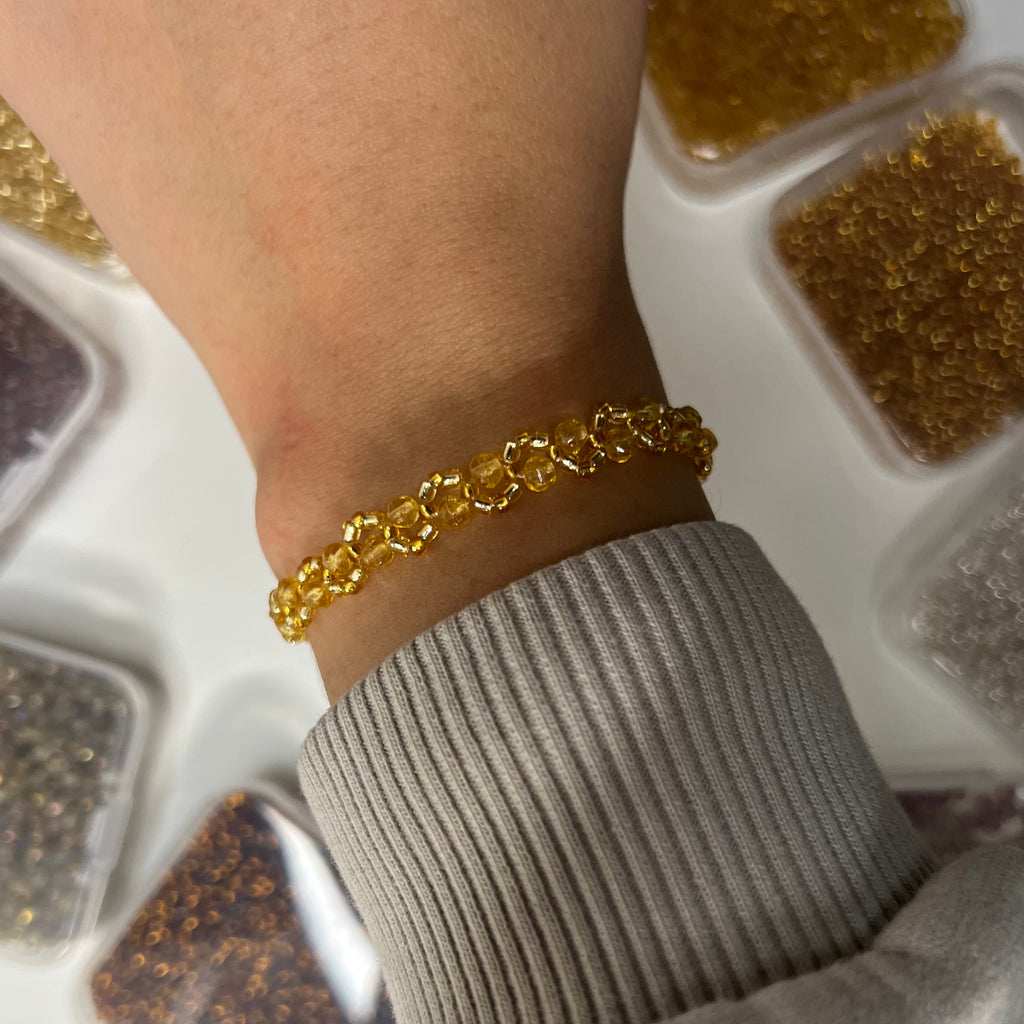 Gold bracelet on a wrist with a neutral background