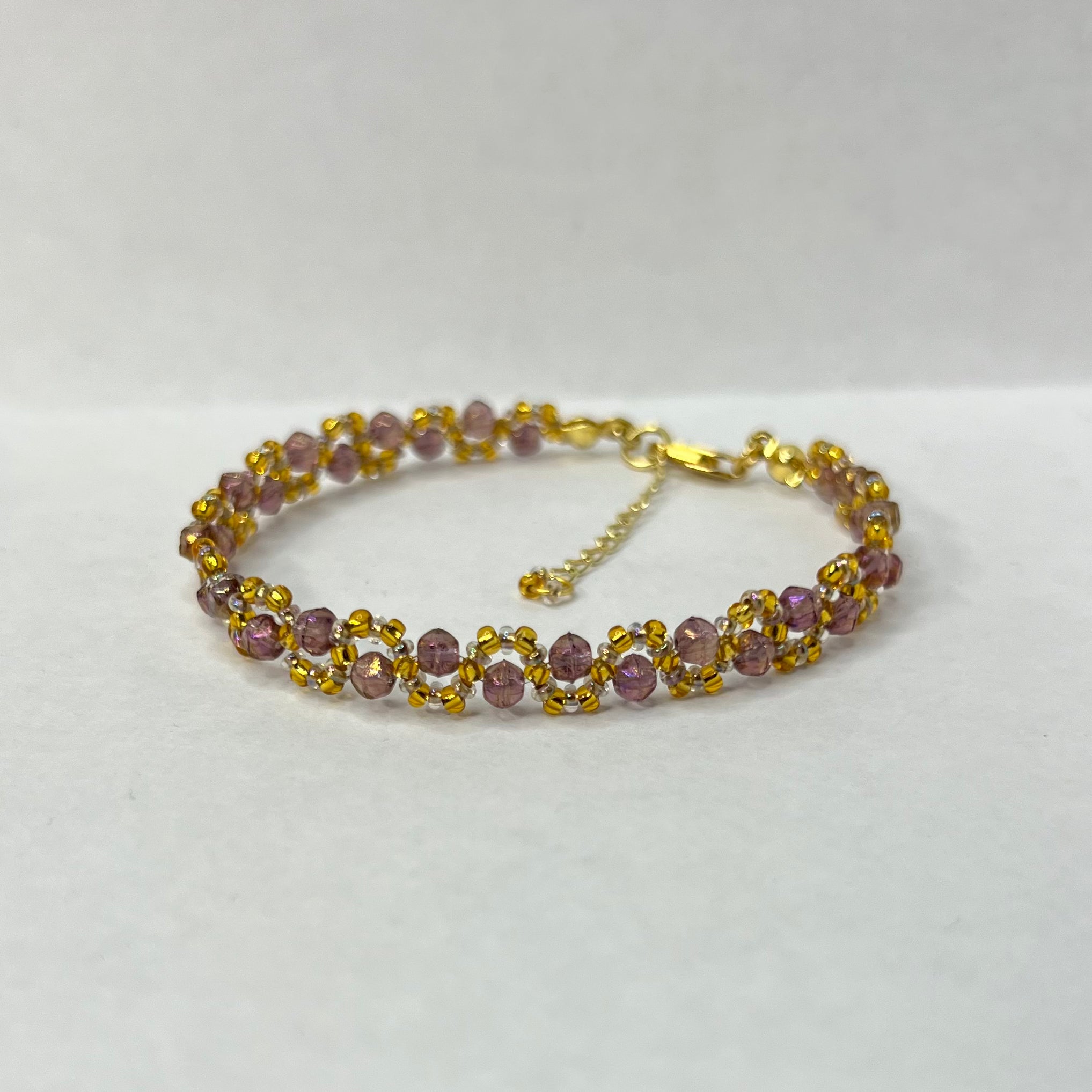 Bracelet with purple beads and gold accents on a white background