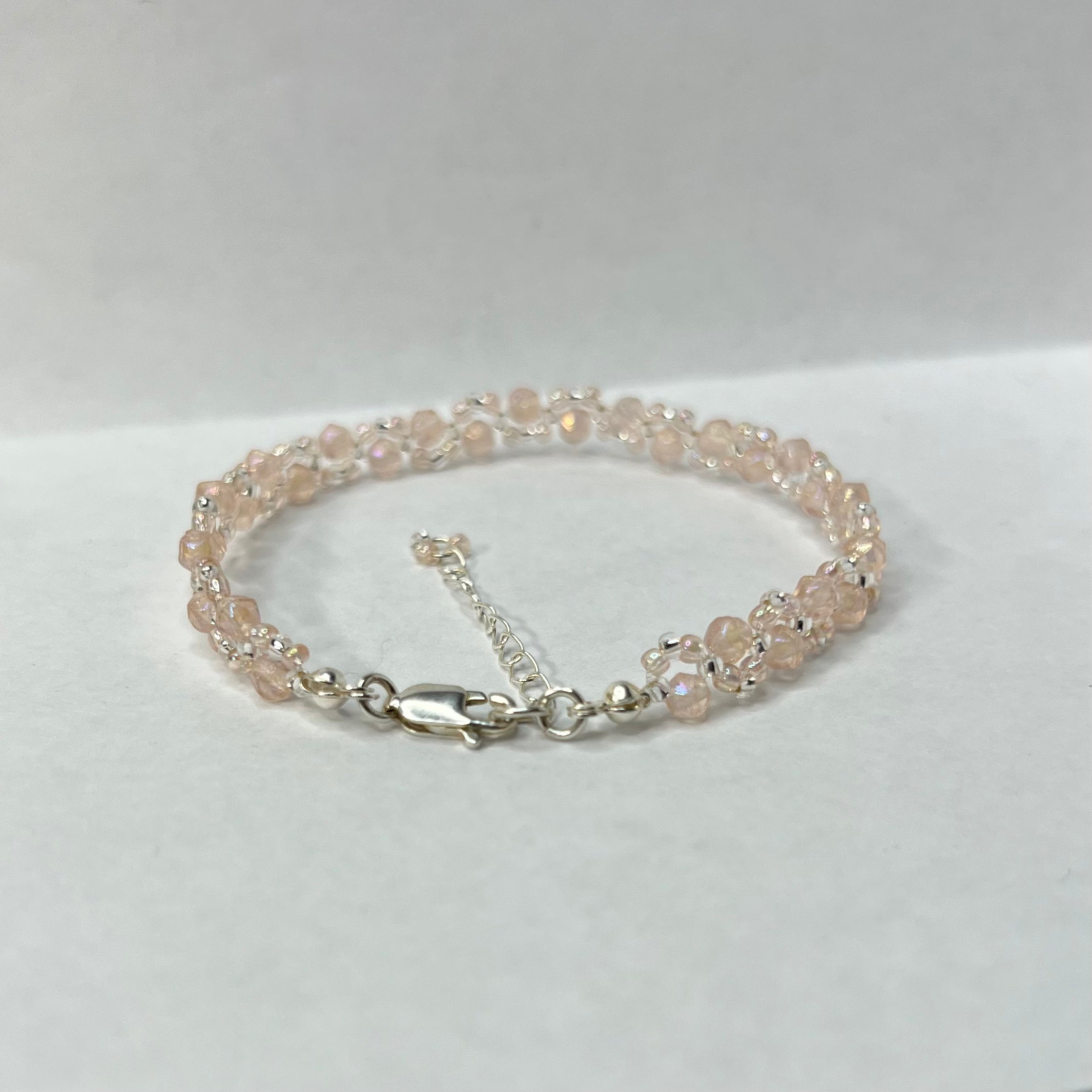 Baby pink beaded bracelet with silver clasp on a white background