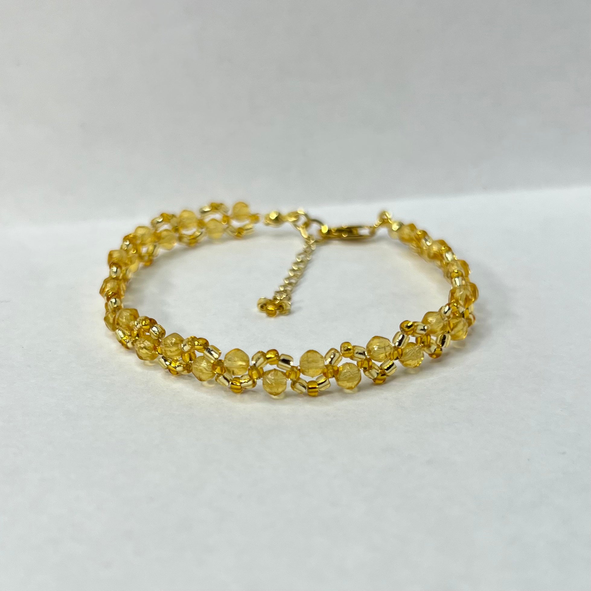 Gold bracelet with yellow beads on a white background