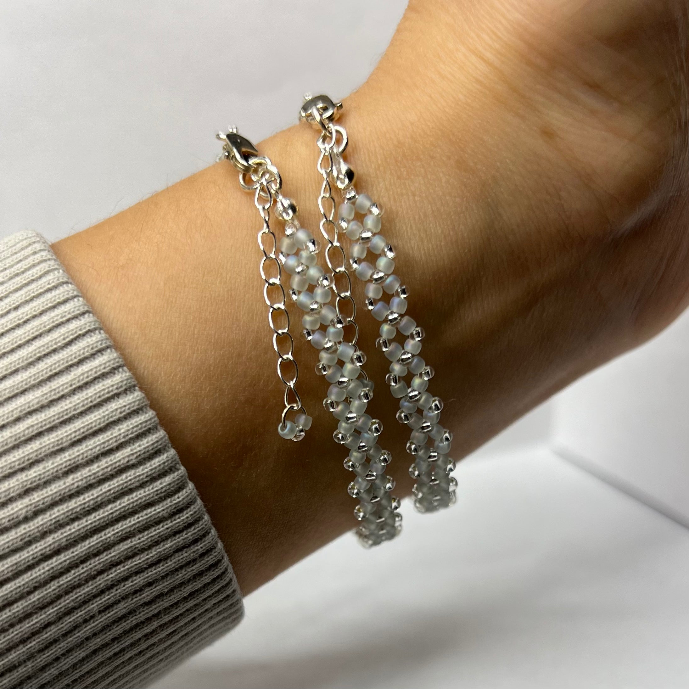 Silver beaded bracelet on a wrist with a neutral background