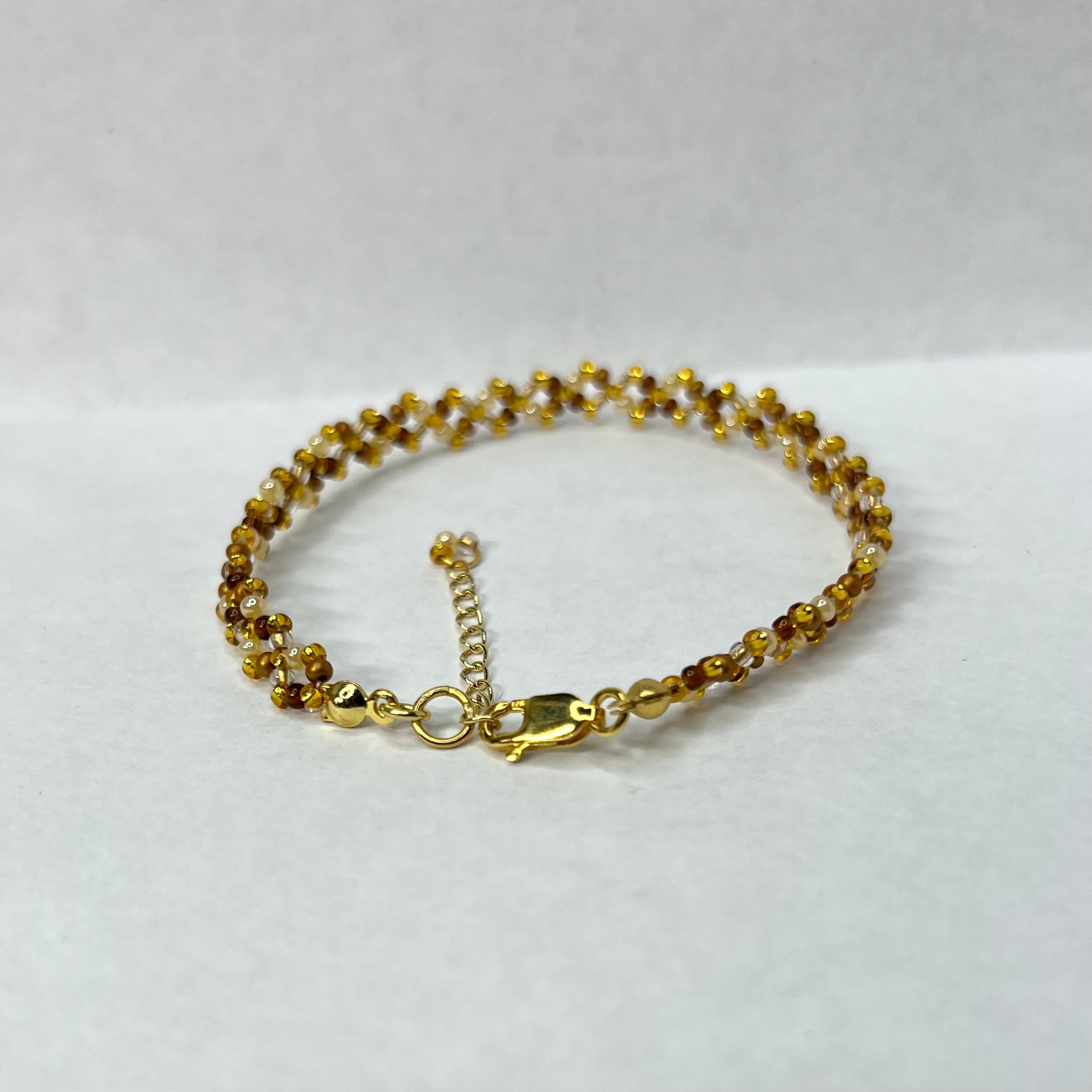 Gold bracelet with small beads on a white background