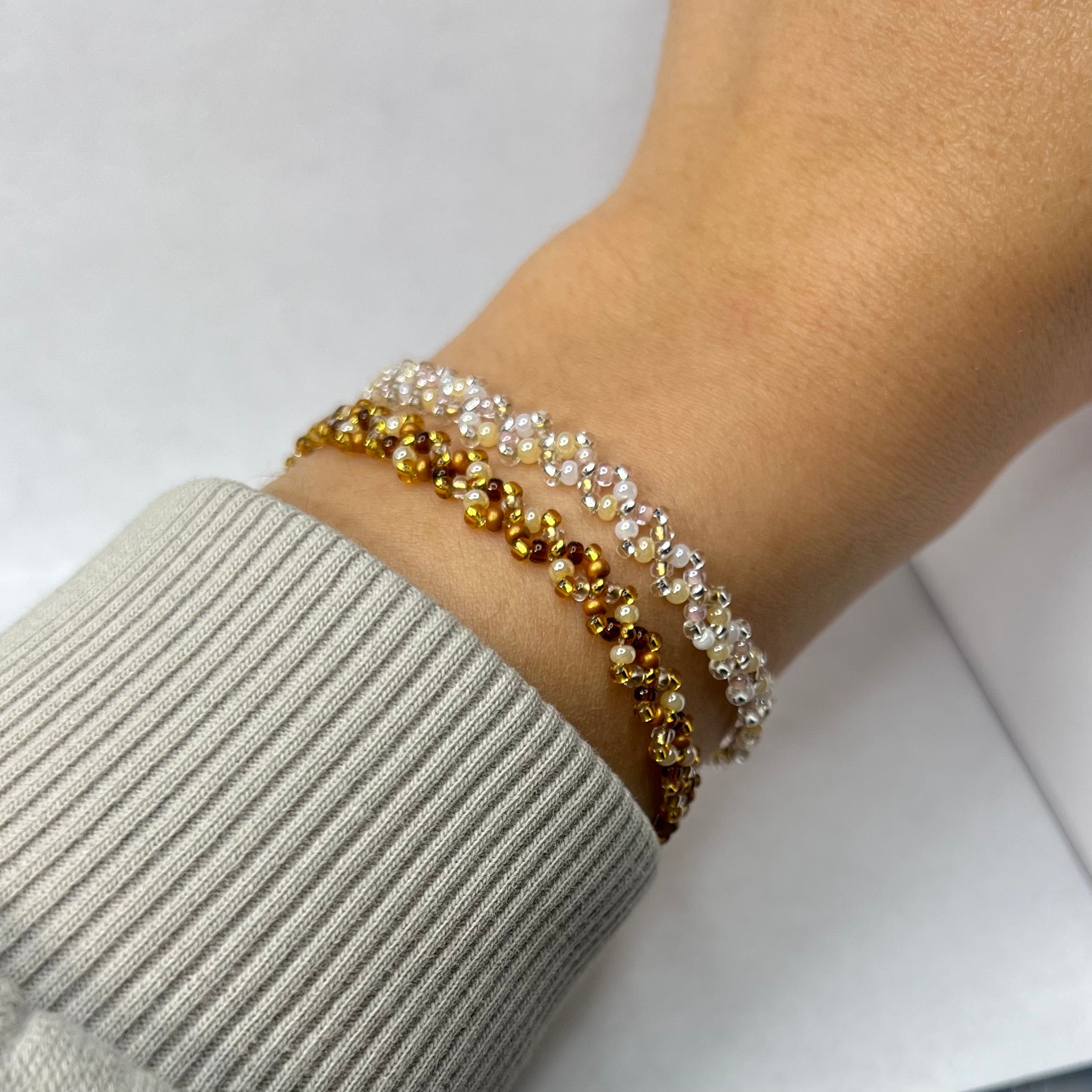 Close-up of a wrist wearing a beaded bracelet on a light background