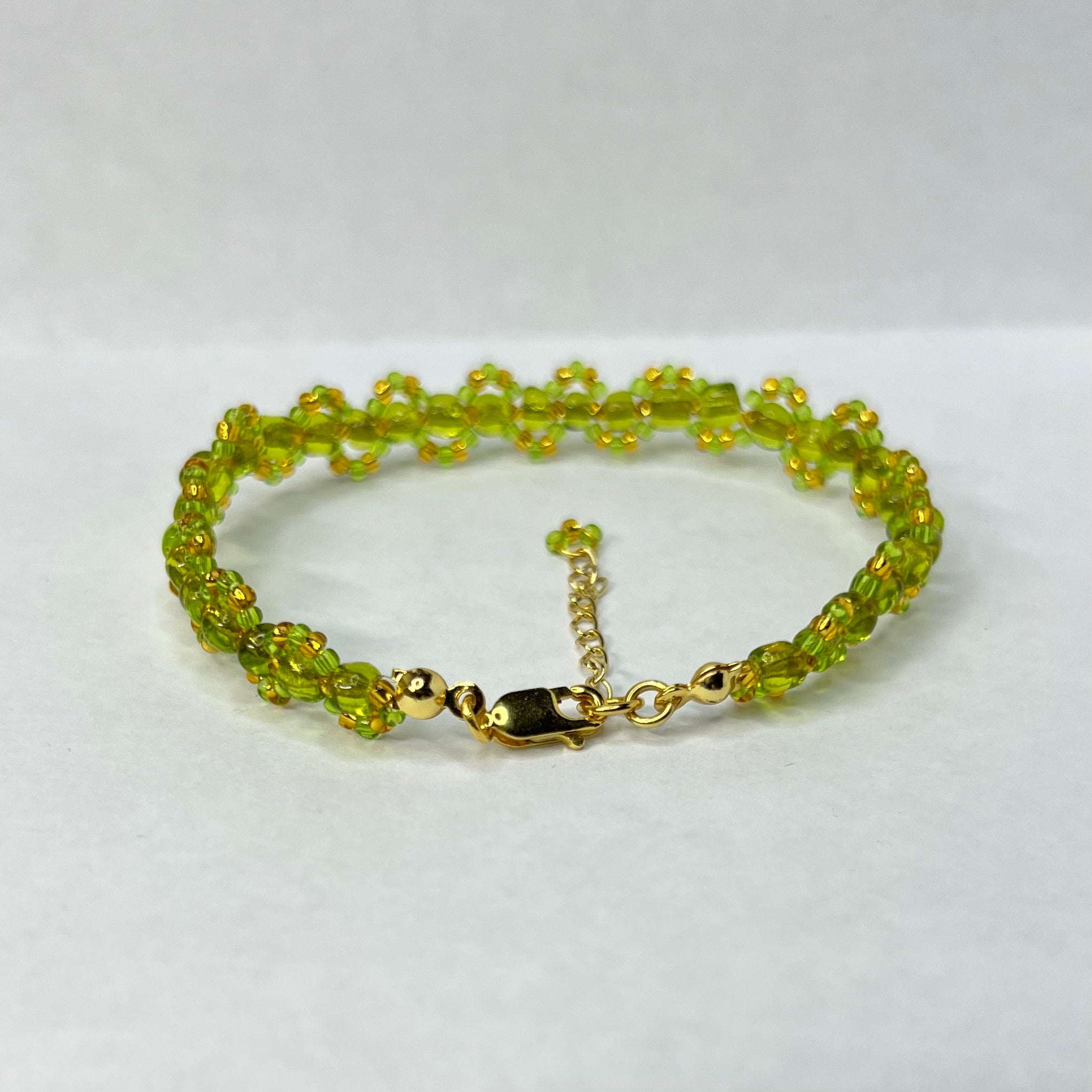 Green beaded bracelet with gold clasp on a white background
