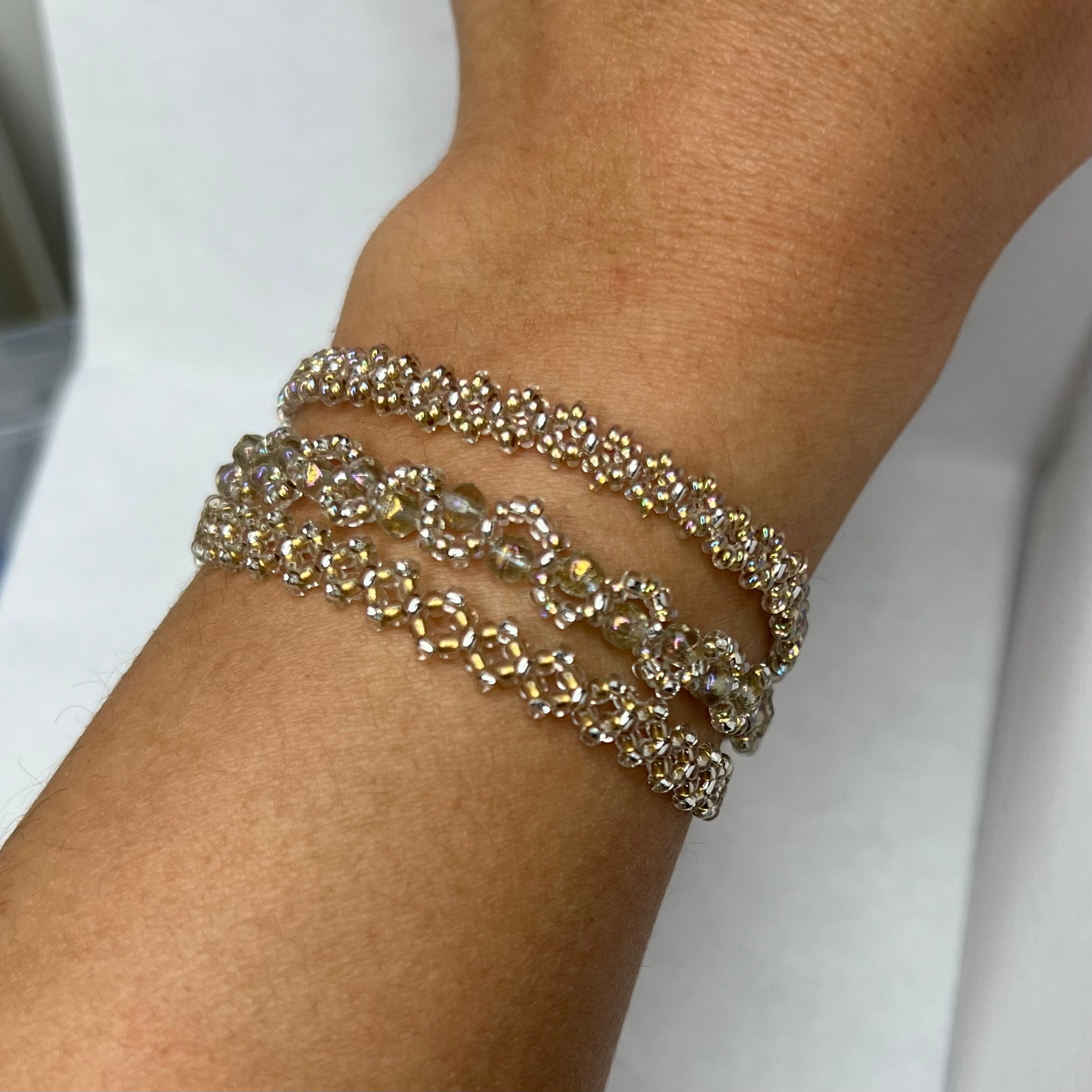 Silver bracelet on a wrist with a plain background