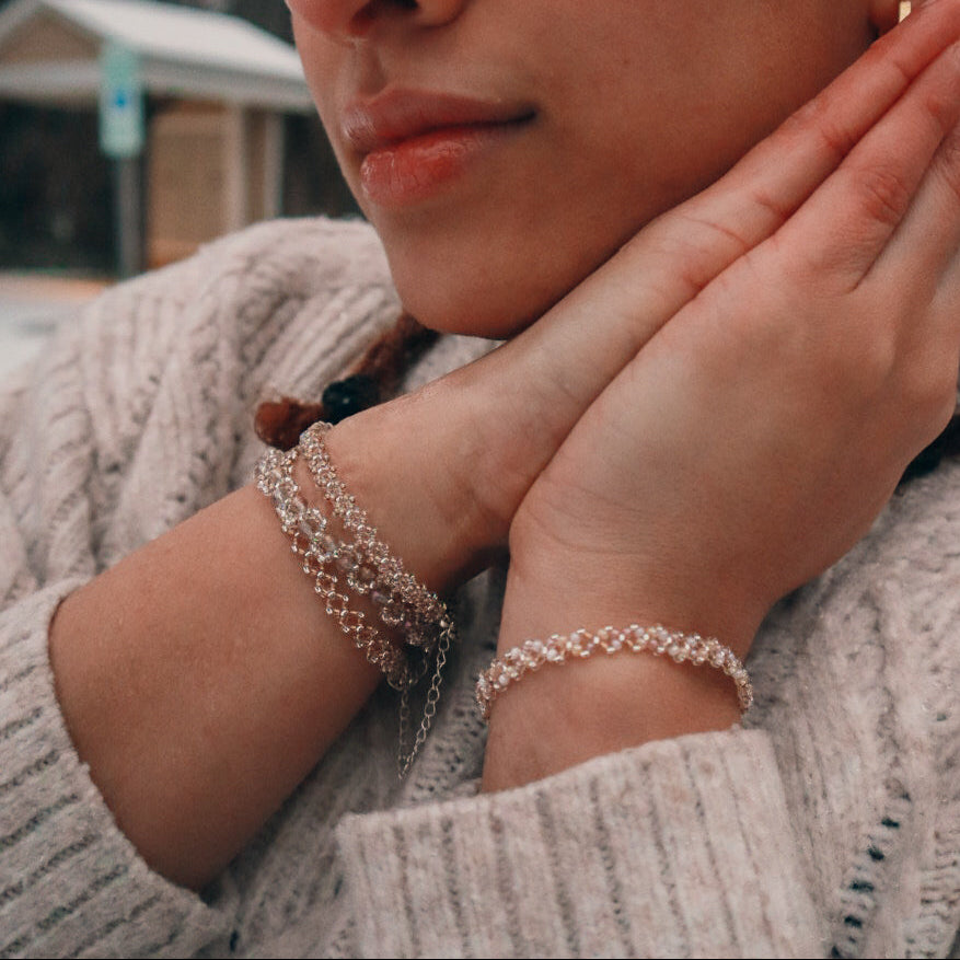 Close-up of a person wearing multiple bracelets on a blurred outdoor background