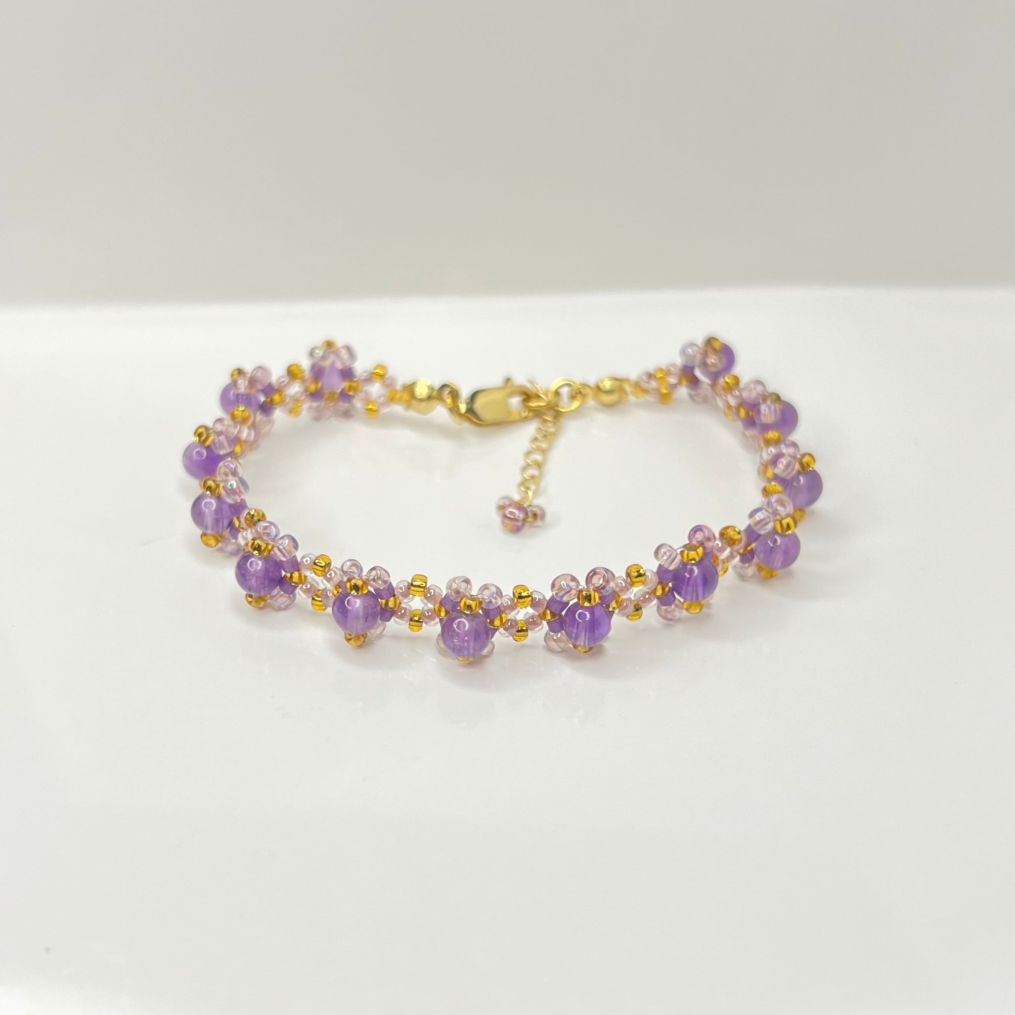 Purple beaded bracelet with gold accents on a white background