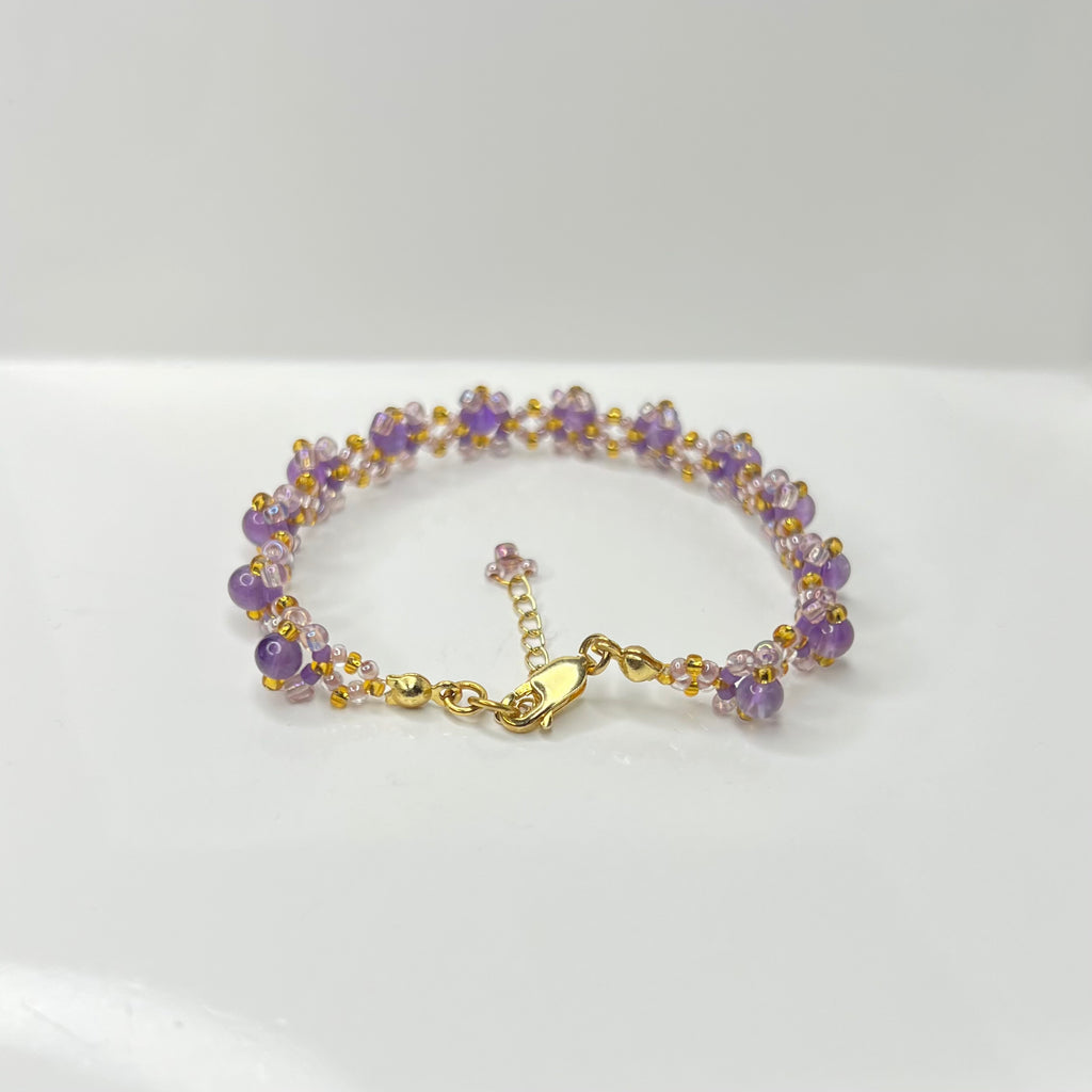Bracelet with purple and gold beads on a white background
