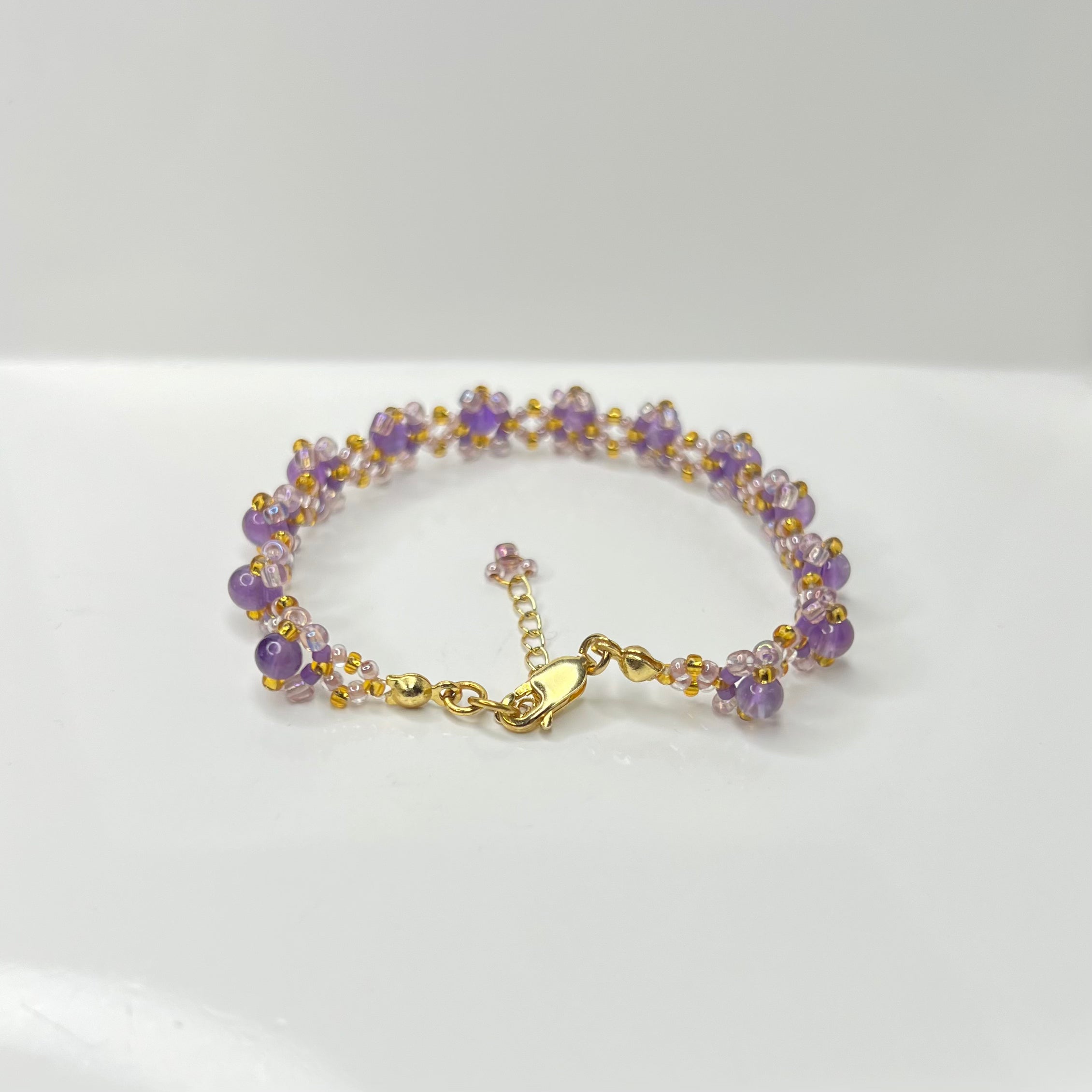 Bracelet with purple and gold beads on a white background