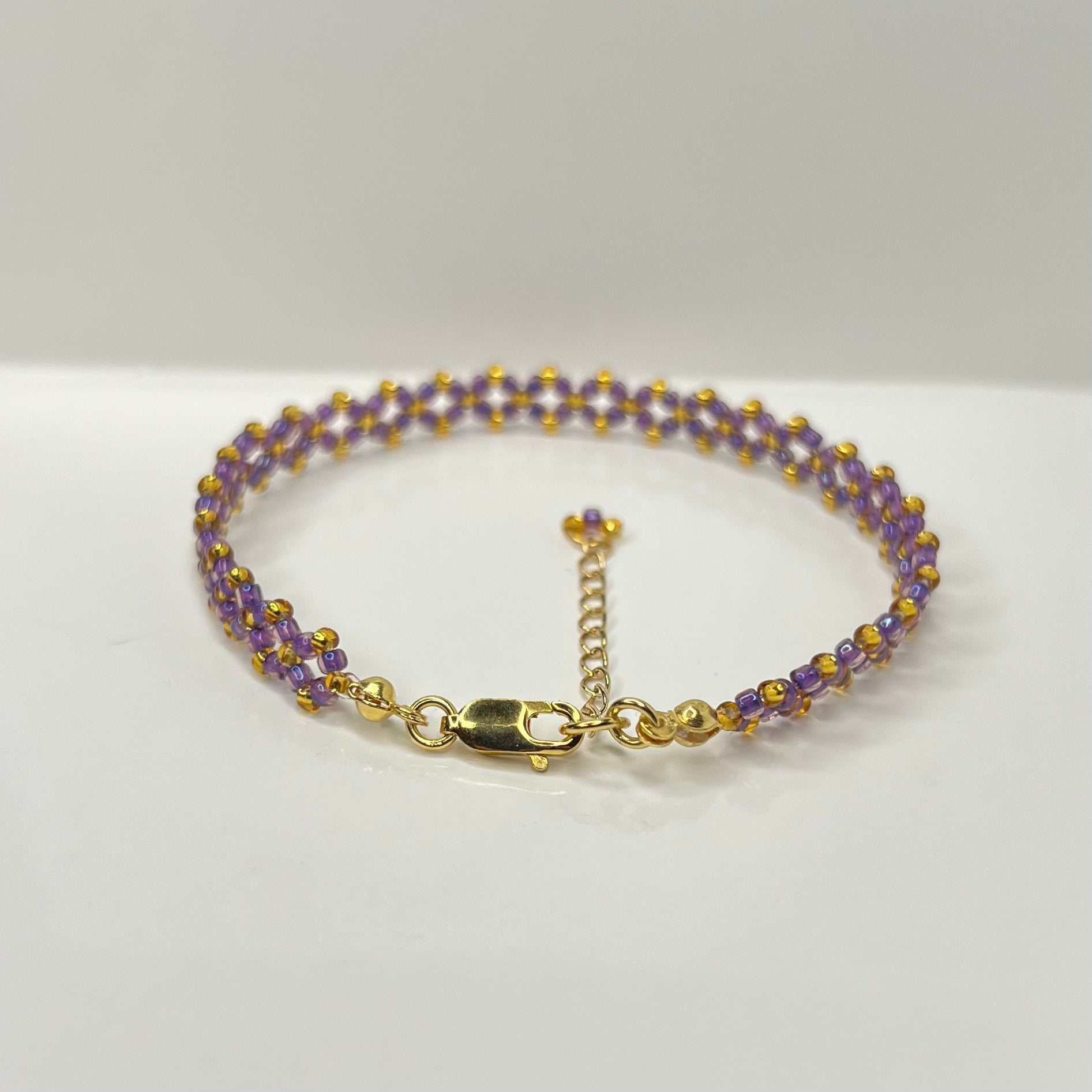 Bracelet with purple beads and gold accents on a white background