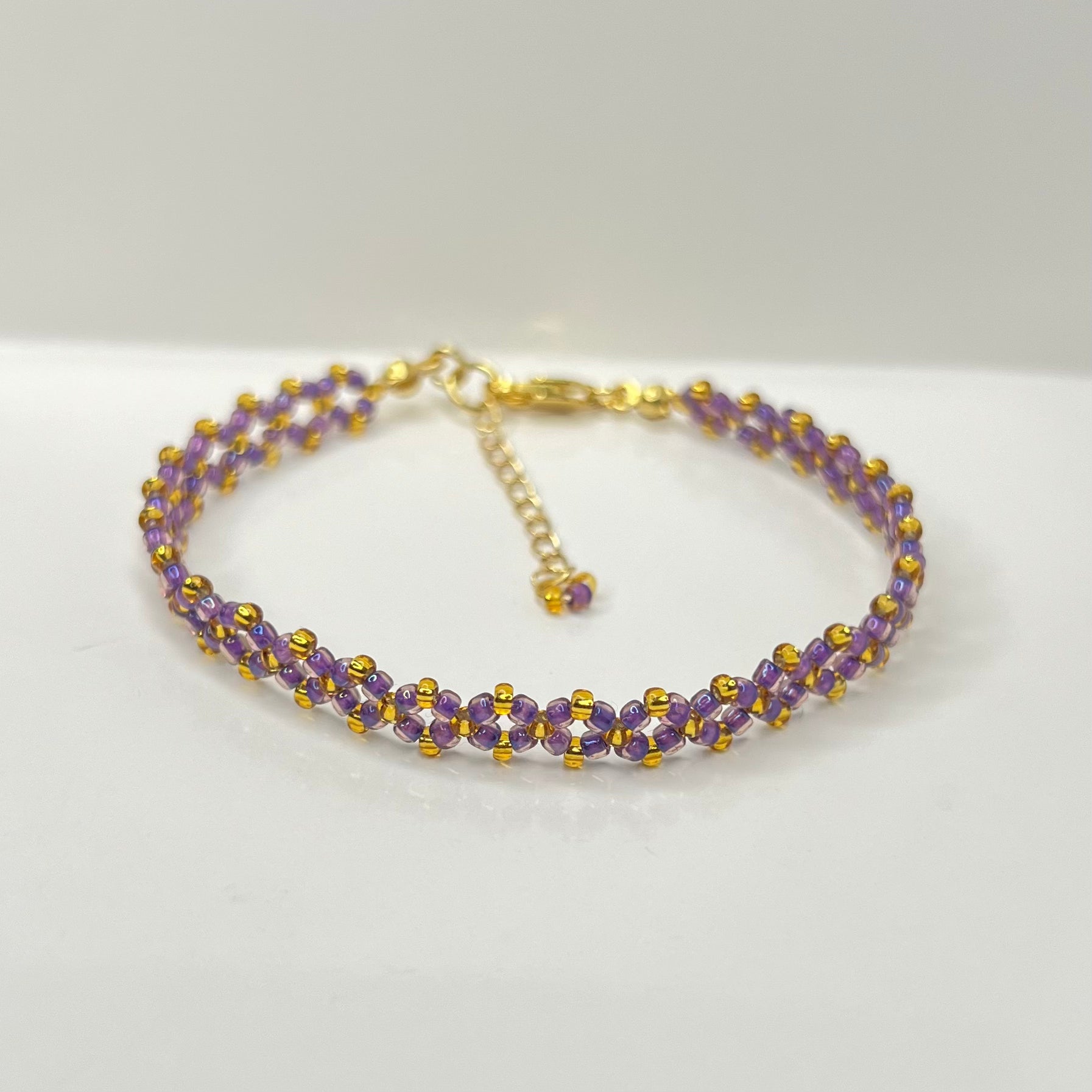 Purple and gold beaded bracelet on a white background