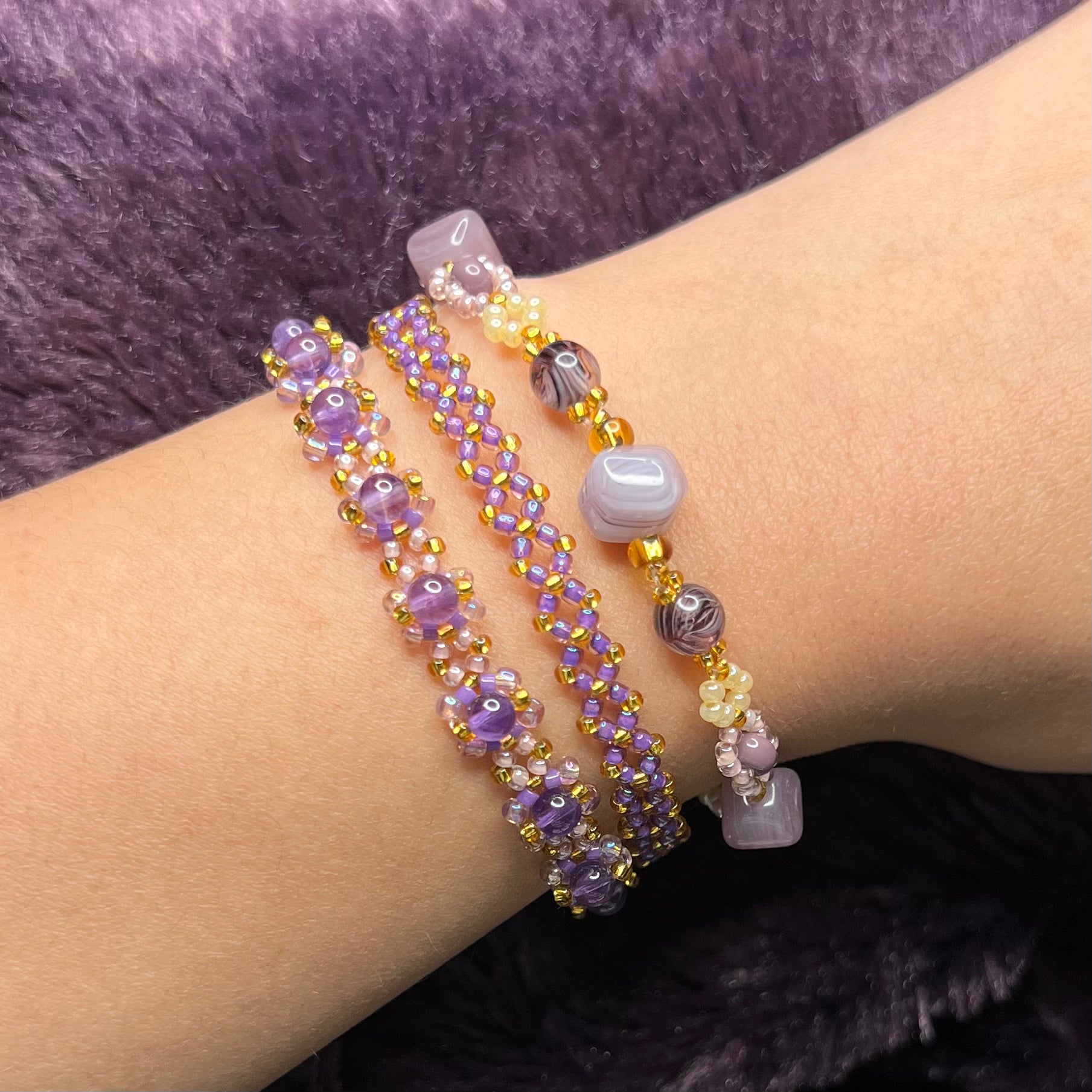 Three beaded bracelets on a wrist with a blurred background