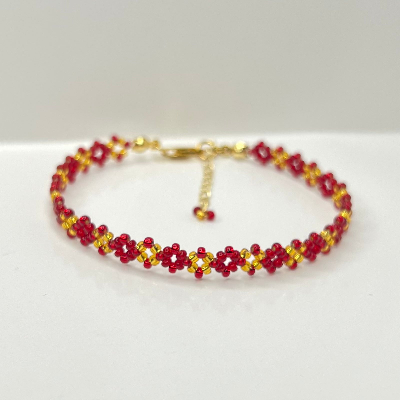 Beaded bracelet with red and gold beads on a white background