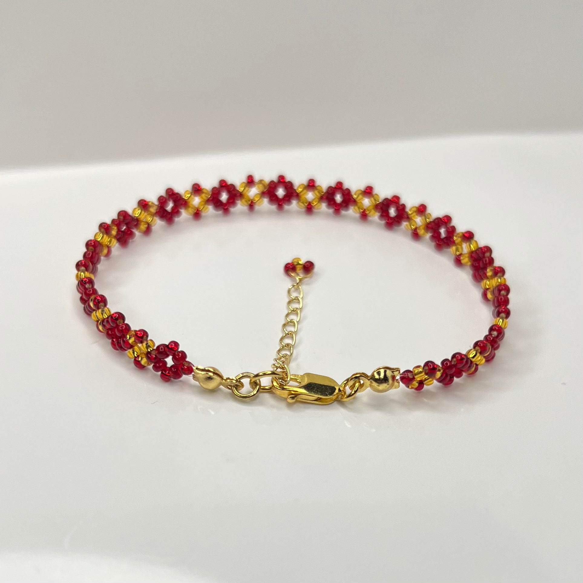 Bracelet with red and gold beads on a white background