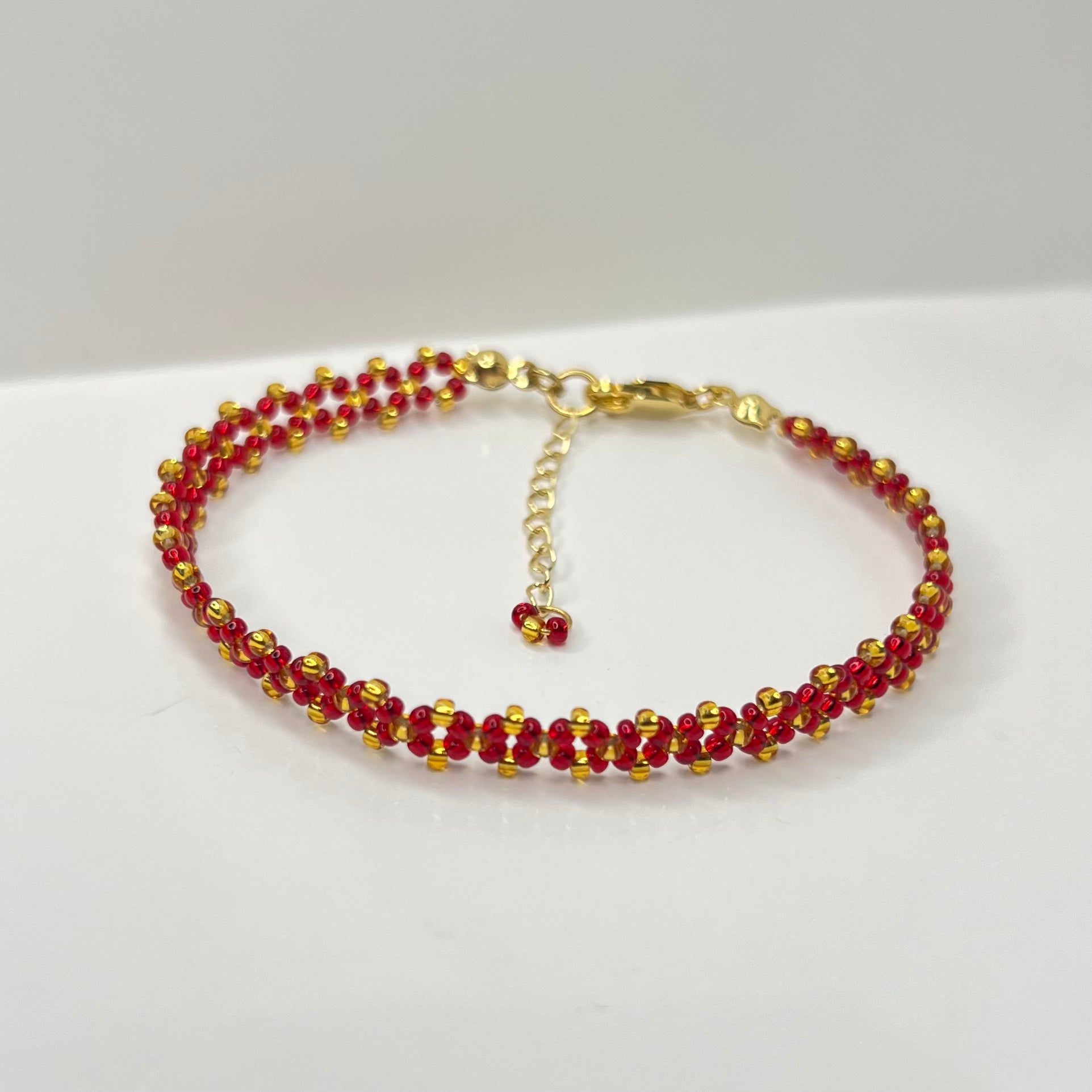 Beaded bracelet with red and gold beads on a white background