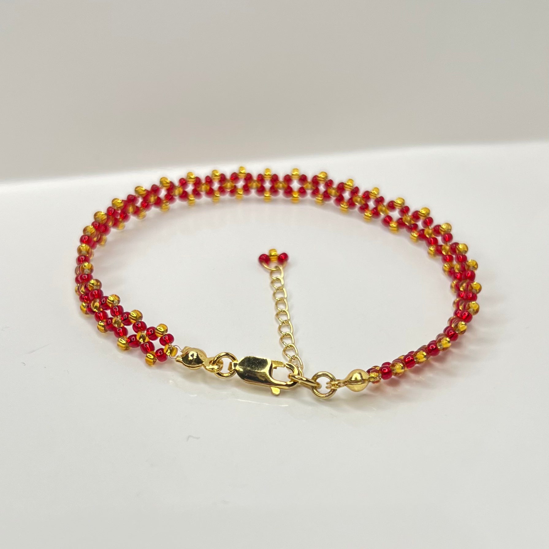 Bracelet with red and gold beads on a white background