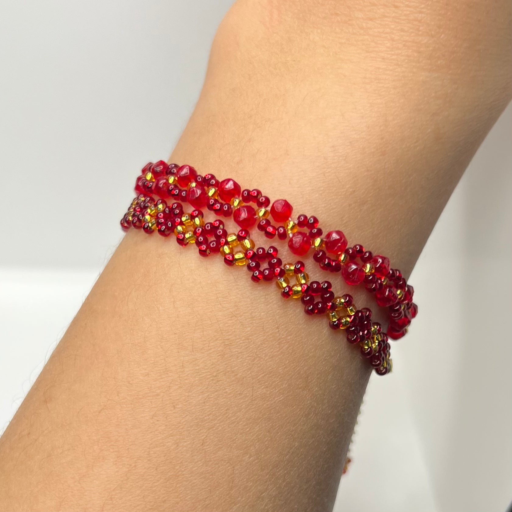 Red beaded bracelet on a wrist against a white background