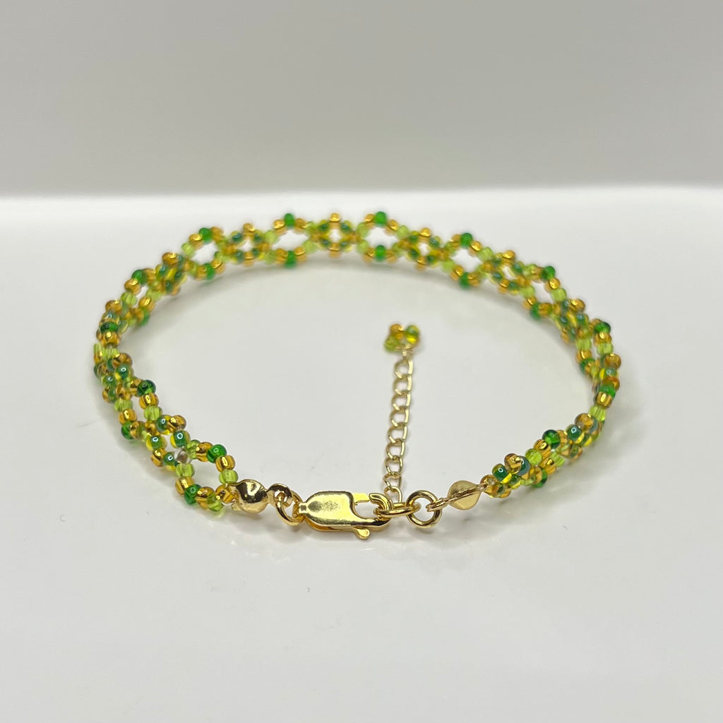 Green beaded bracelet with gold clasp on a white background