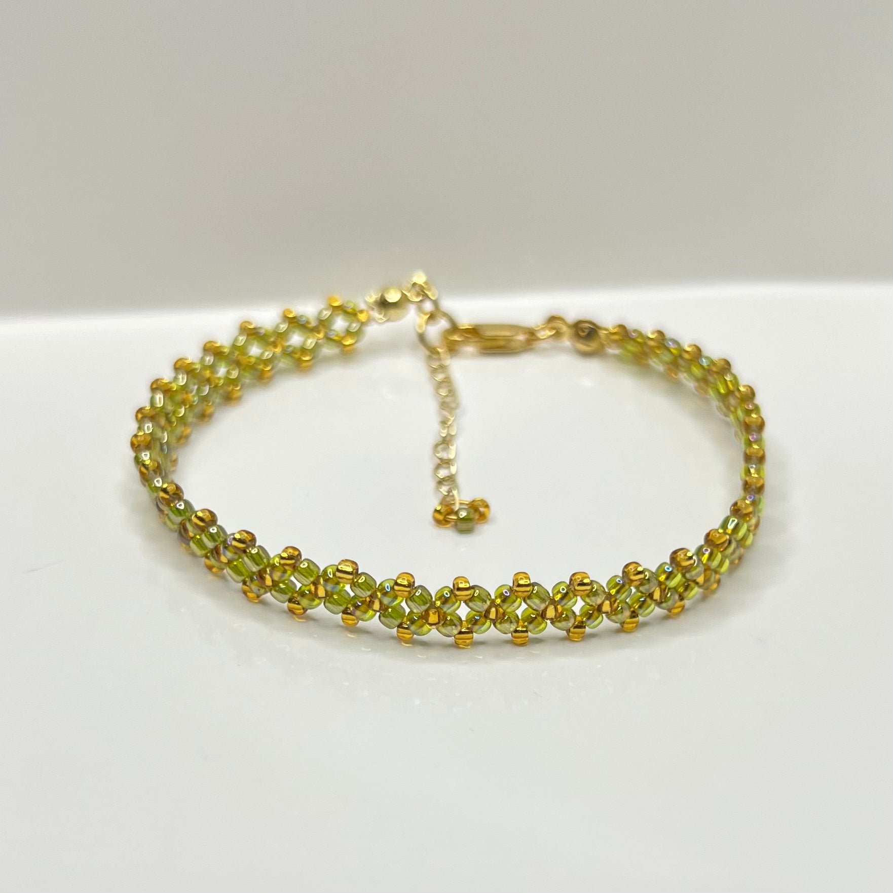 Olive green and gold bracelet on a white background