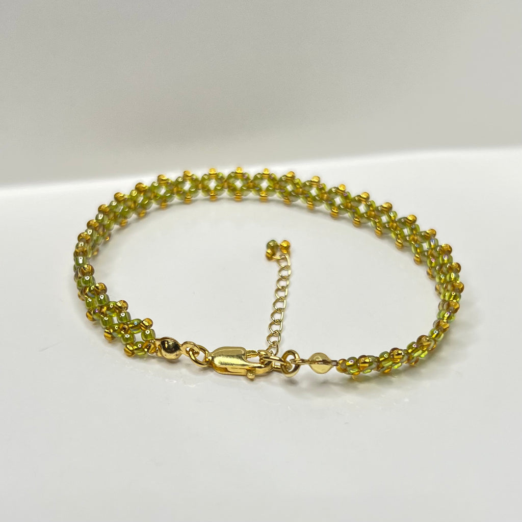 Olive green and gold beaded bracelet on a white background