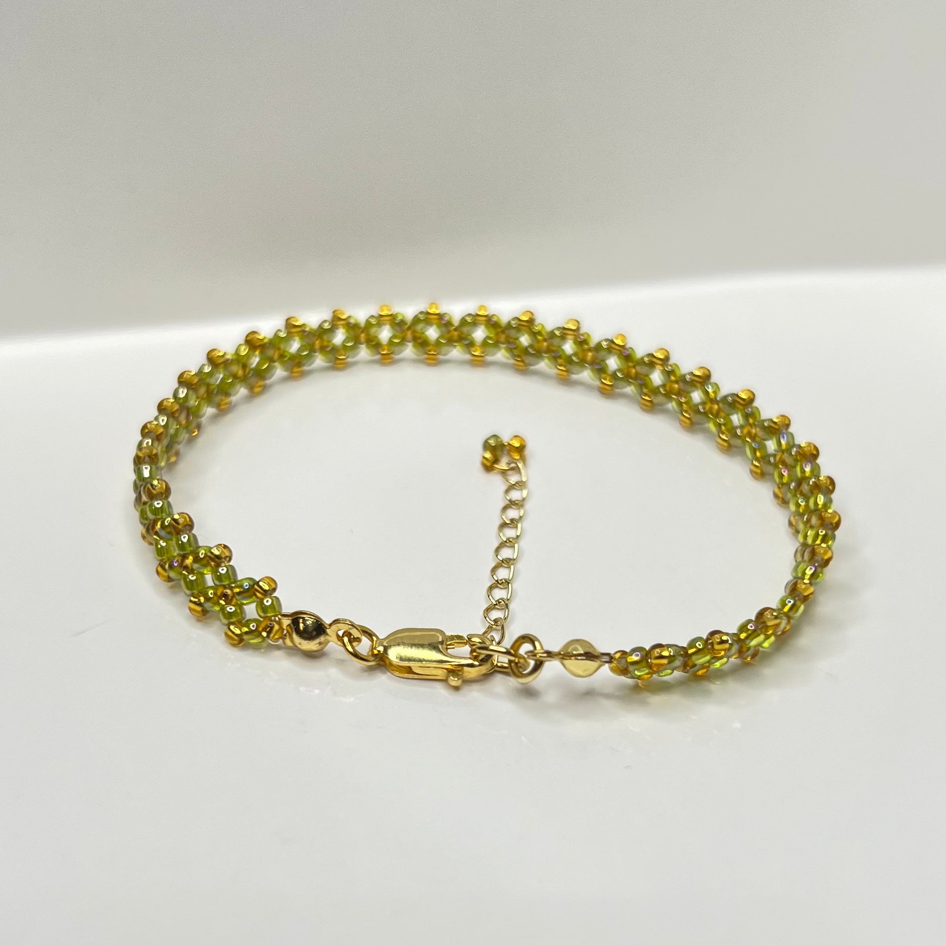 Olive green and gold beaded bracelet on a white background