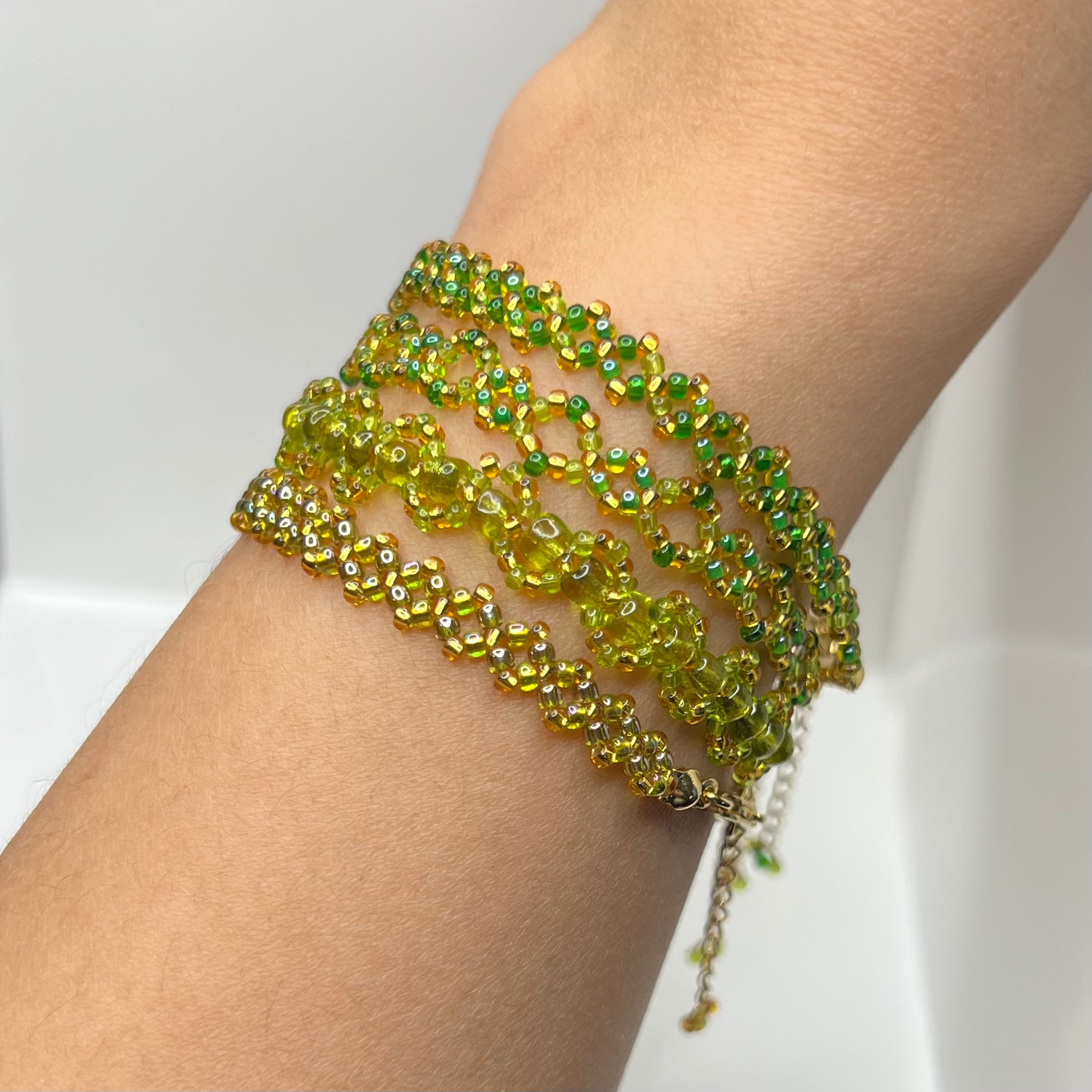 Green beaded bracelets on a wrist against a white background
