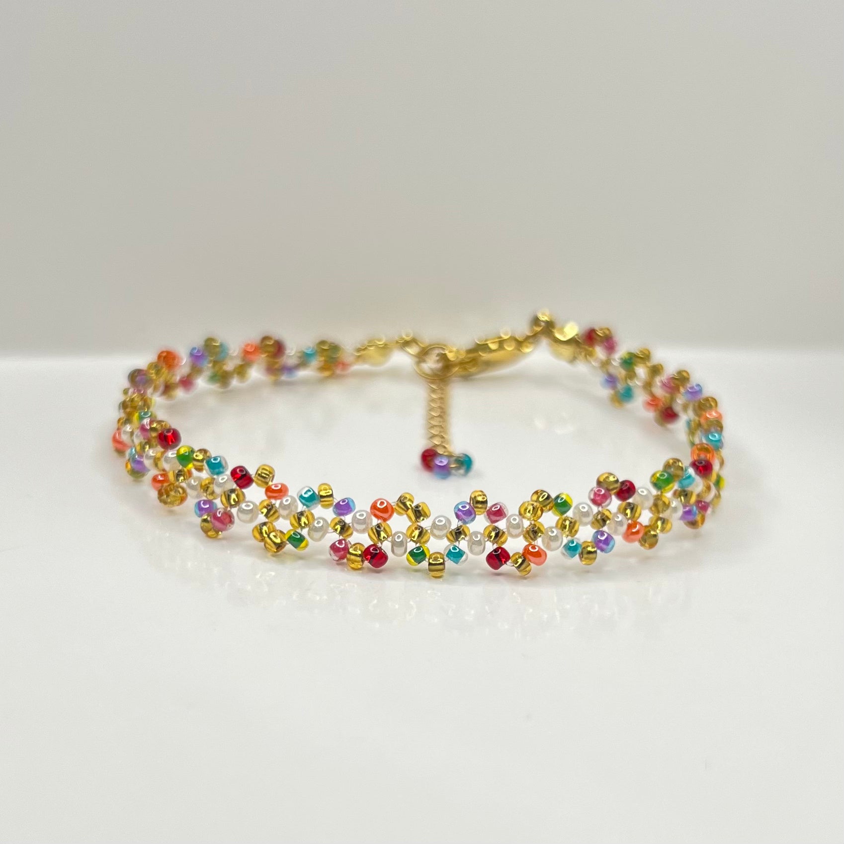 Multicolored beaded bracelet on a white surface with a light gray background