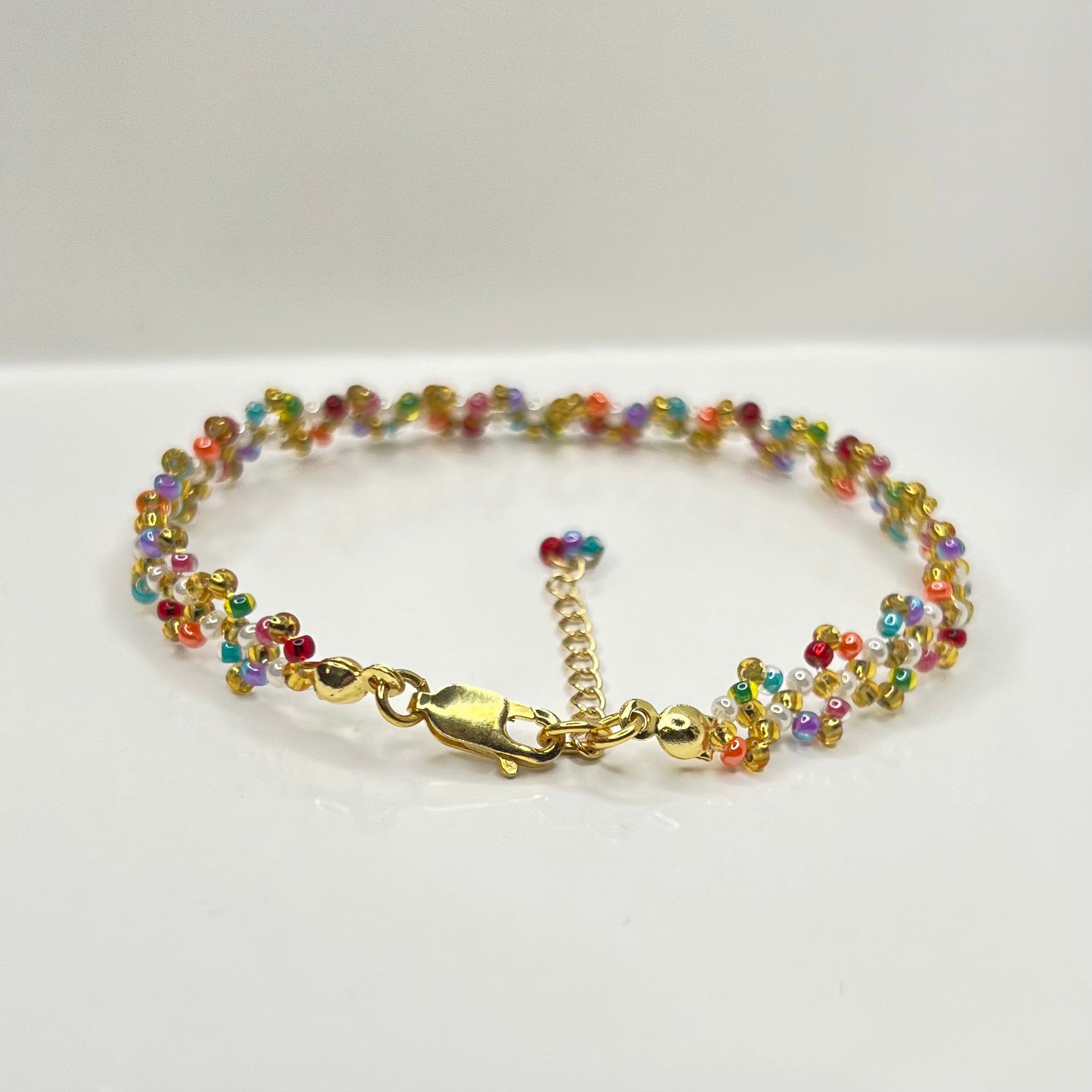 Multicolored beaded bracelet with gold clasp on a white background