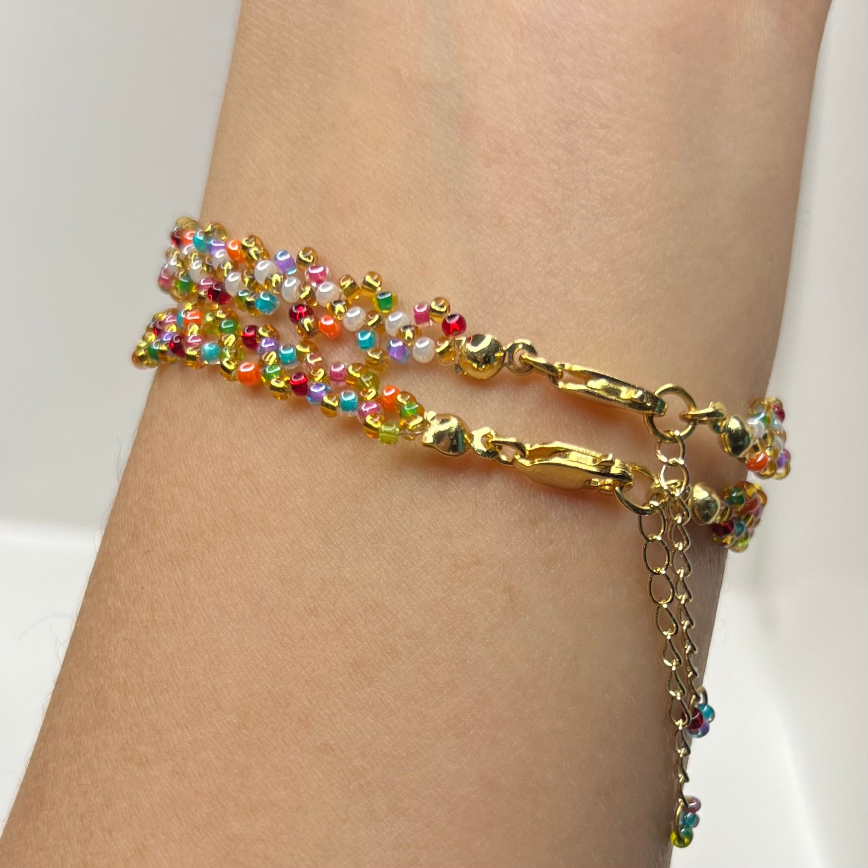 Multicolored beaded bracelet on a wrist with a gold chain