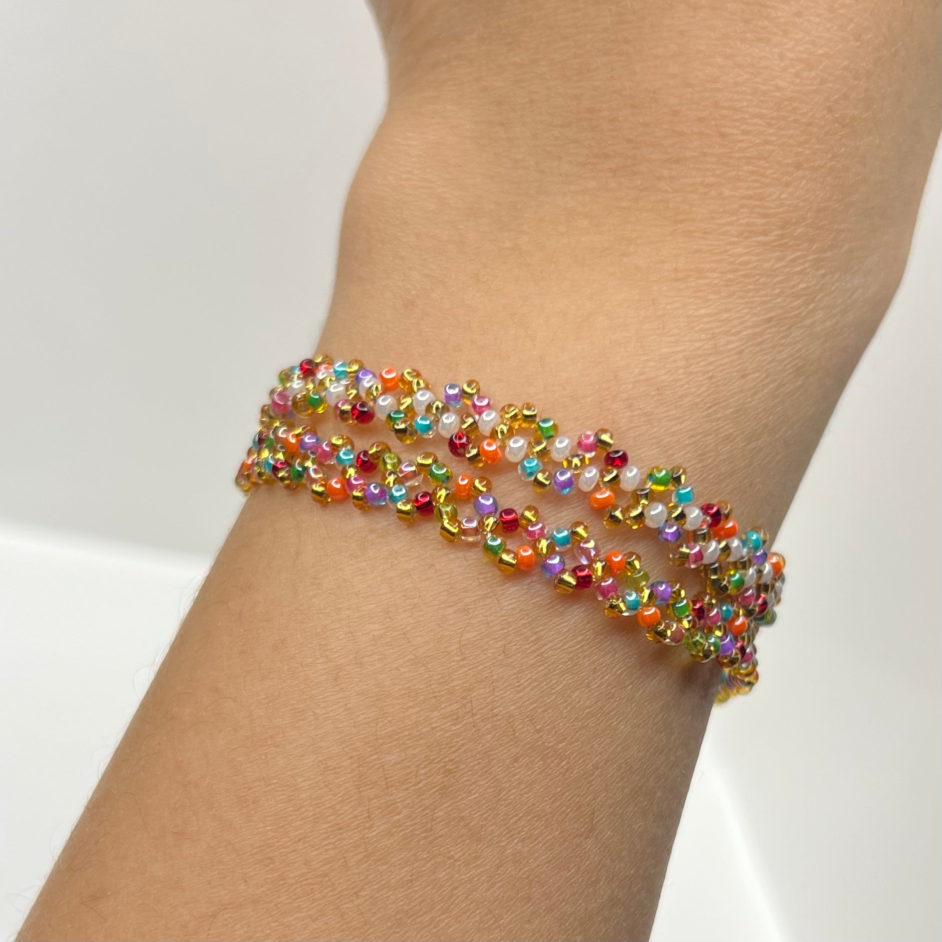 Multicolored beaded bracelet on a wrist against a neutral background