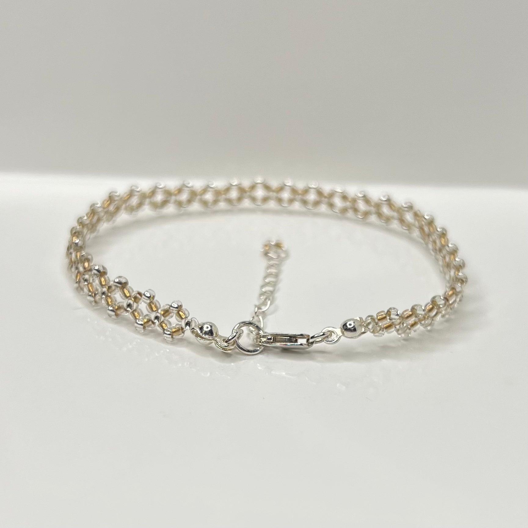 Silver chain bracelet on a white surface with a light gray background