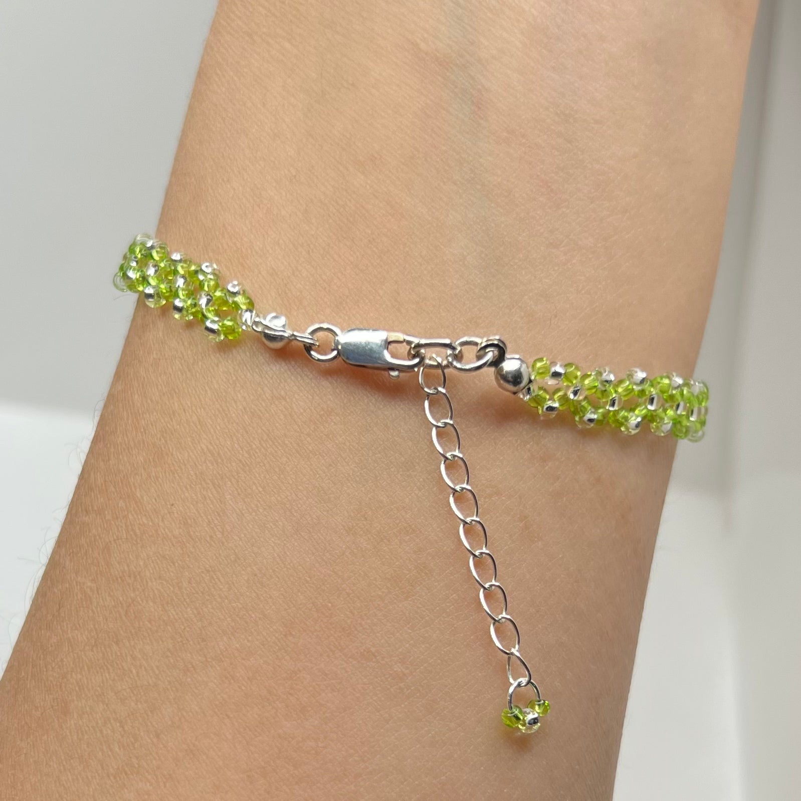 Green beaded bracelet on a wrist with a white background