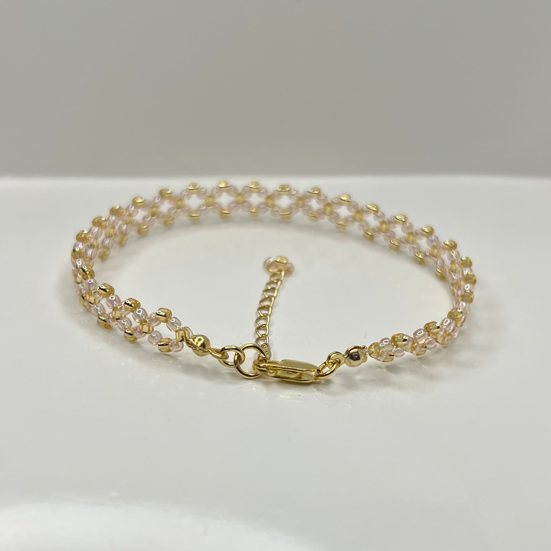 Gold and soft pink bracelet on a white background