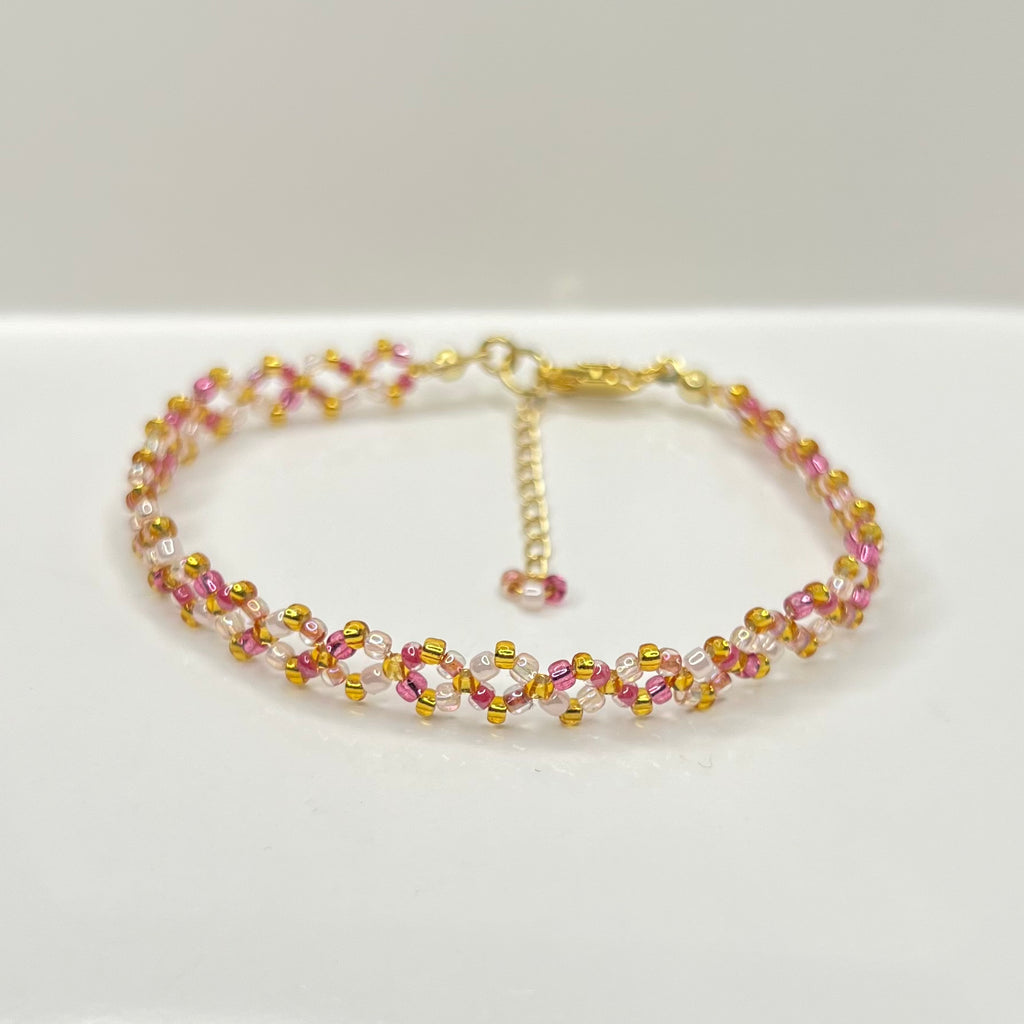 Beaded bracelet with pink and gold beads on a white background